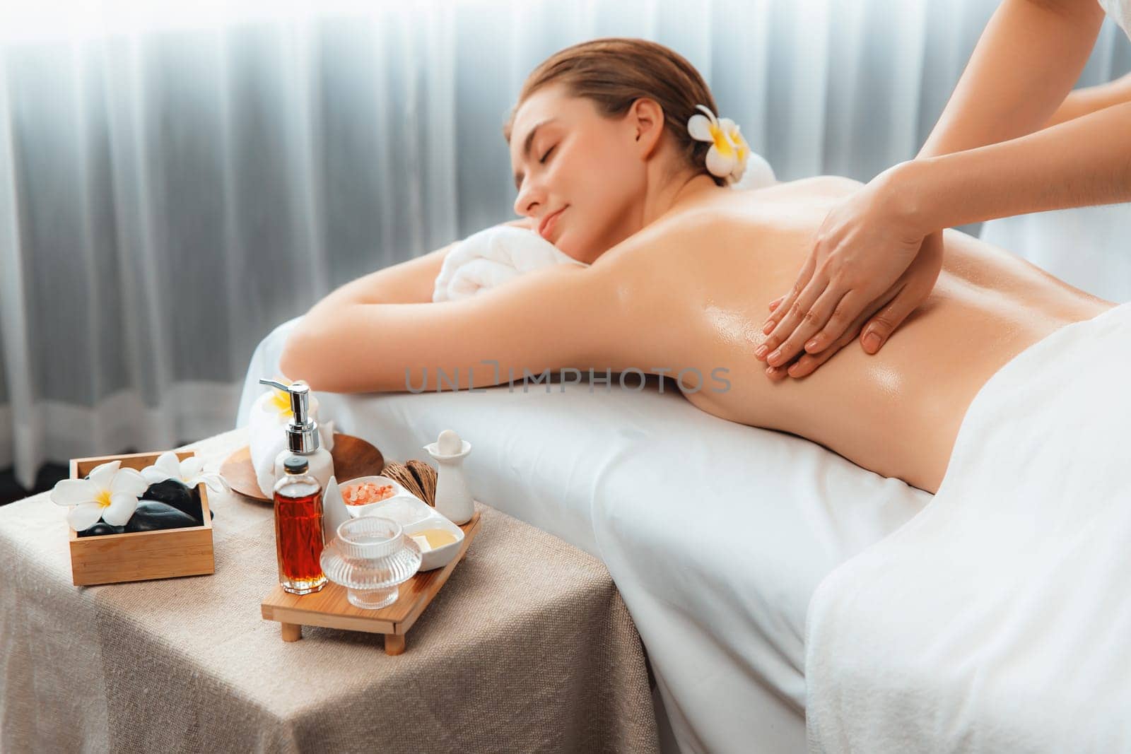 Caucasian woman customer enjoying relaxing anti-stress spa massage and pampering with beauty skin recreation leisure in day light ambient salon spa at luxury resort or hotel. Quiescent