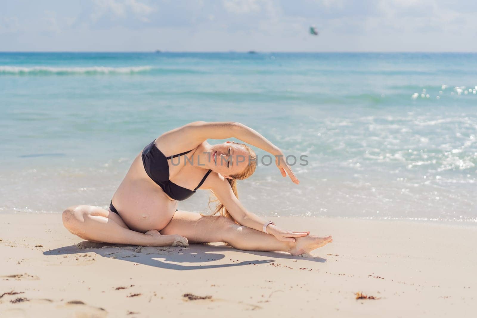 Harmonizing mind and body, a pregnant woman gracefully practices yoga on the beach, embracing the serenity of the seaside for a tranquil and mindful pregnancy experience.