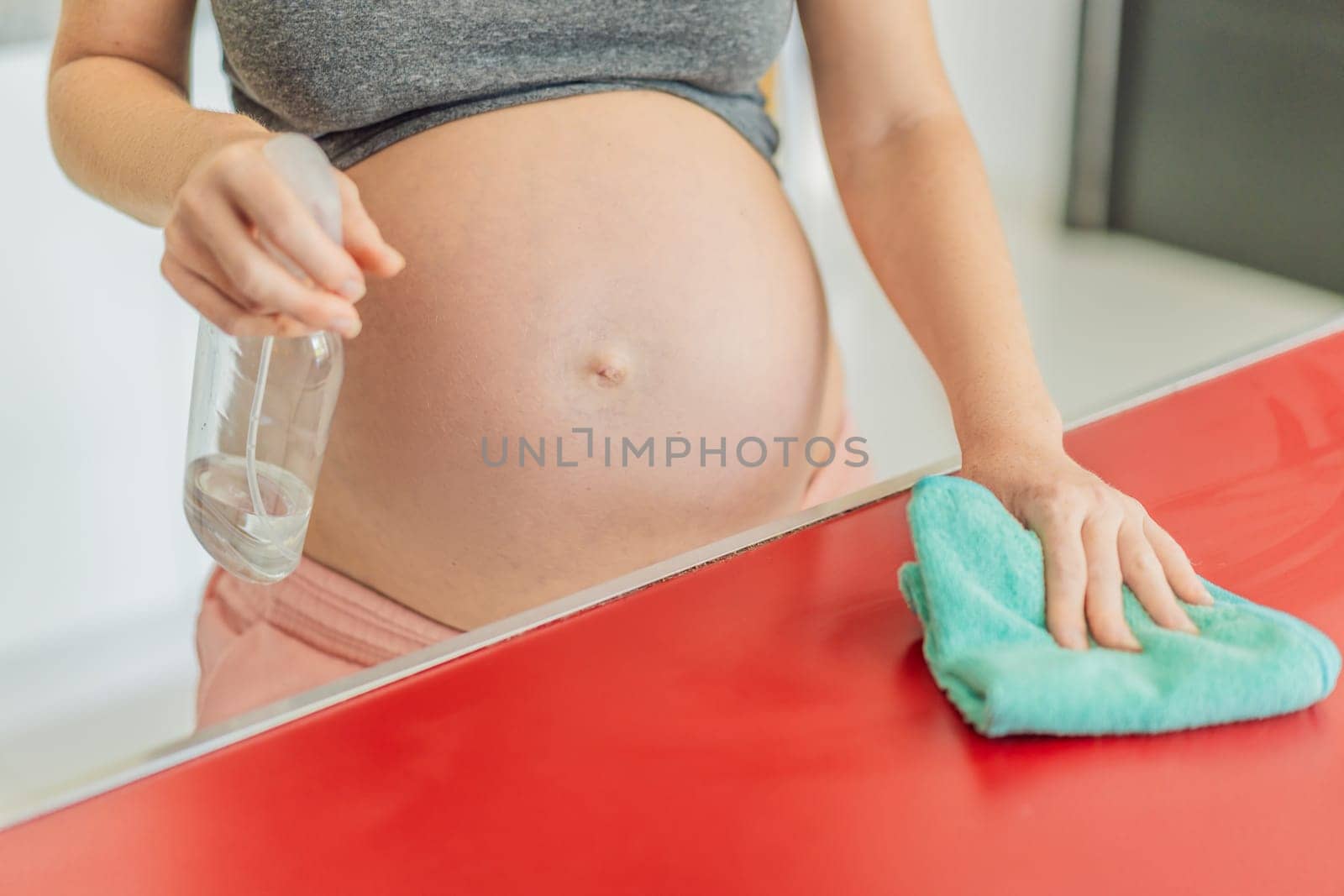 Efficient and dedicated, a pregnant woman tackles kitchen chores, ensuring a clean and organized space, exemplifying resilience and care during her pregnancy by galitskaya