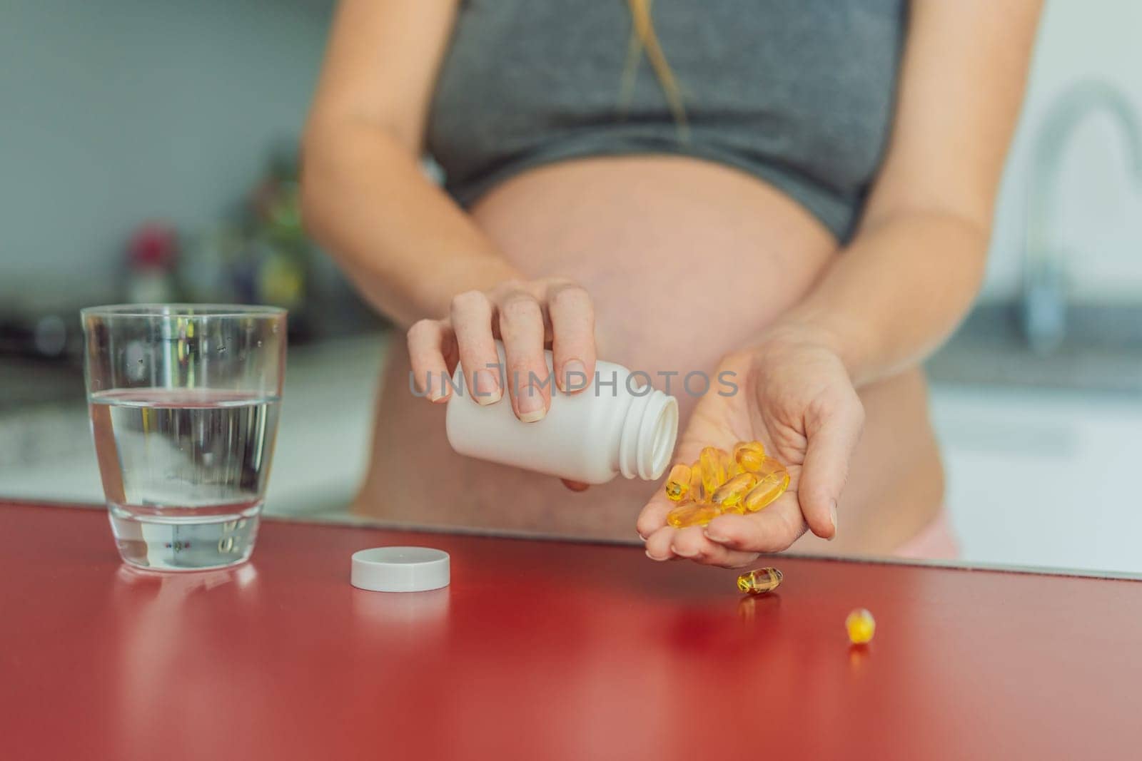 pregnant woman conscientiously takes fish oil capsules, rich in omega-3, prioritizing essential nutrients for a healthy pregnancy journey by galitskaya