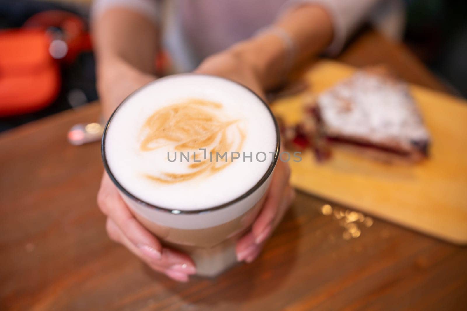 woman hands with latte on a wood table in cafe.