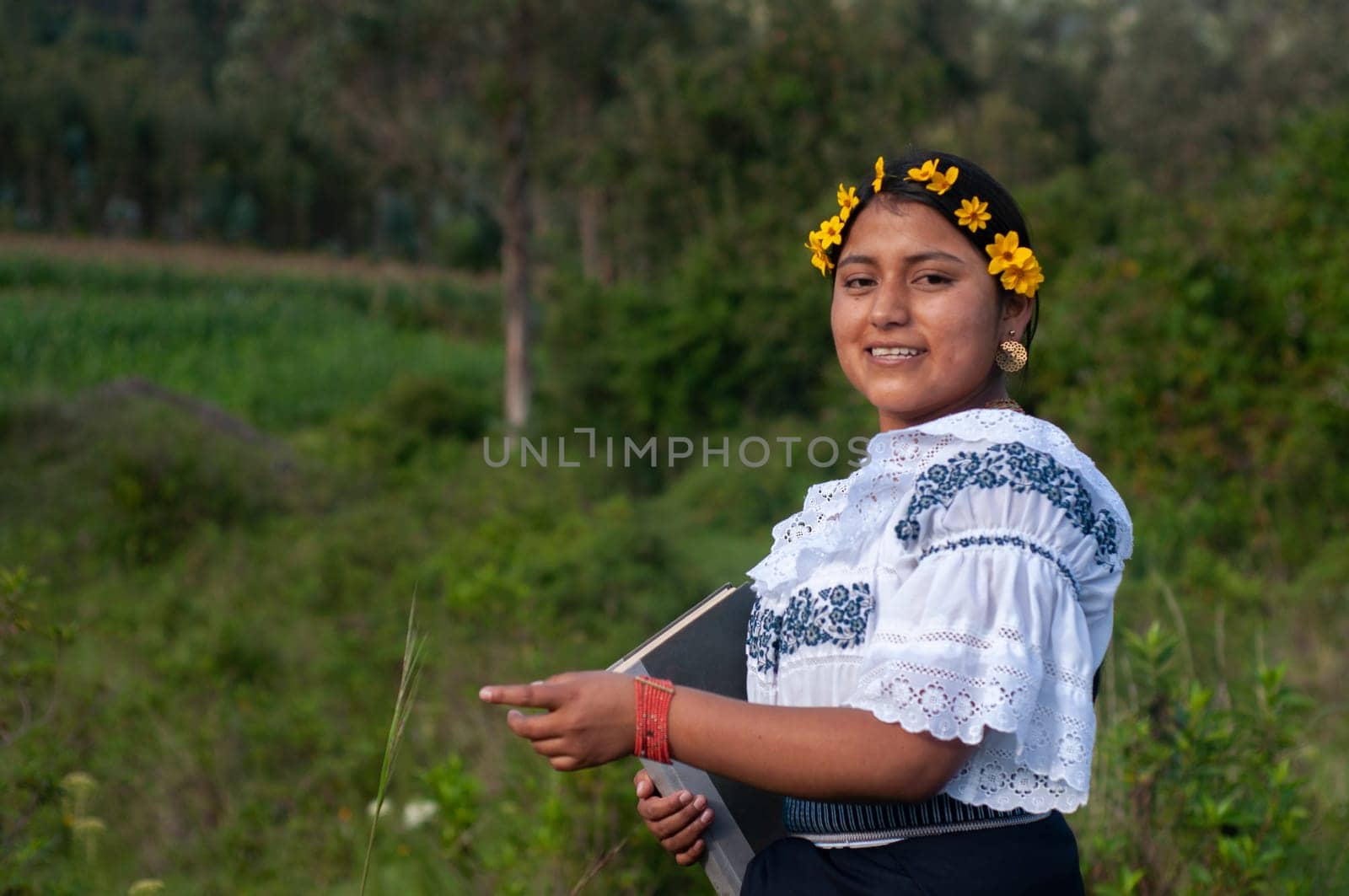 copy space de A cheerful Indian woman with yellow flowers in her hair poses for a photograph with a book in her hand. book day. springtime by Raulmartin