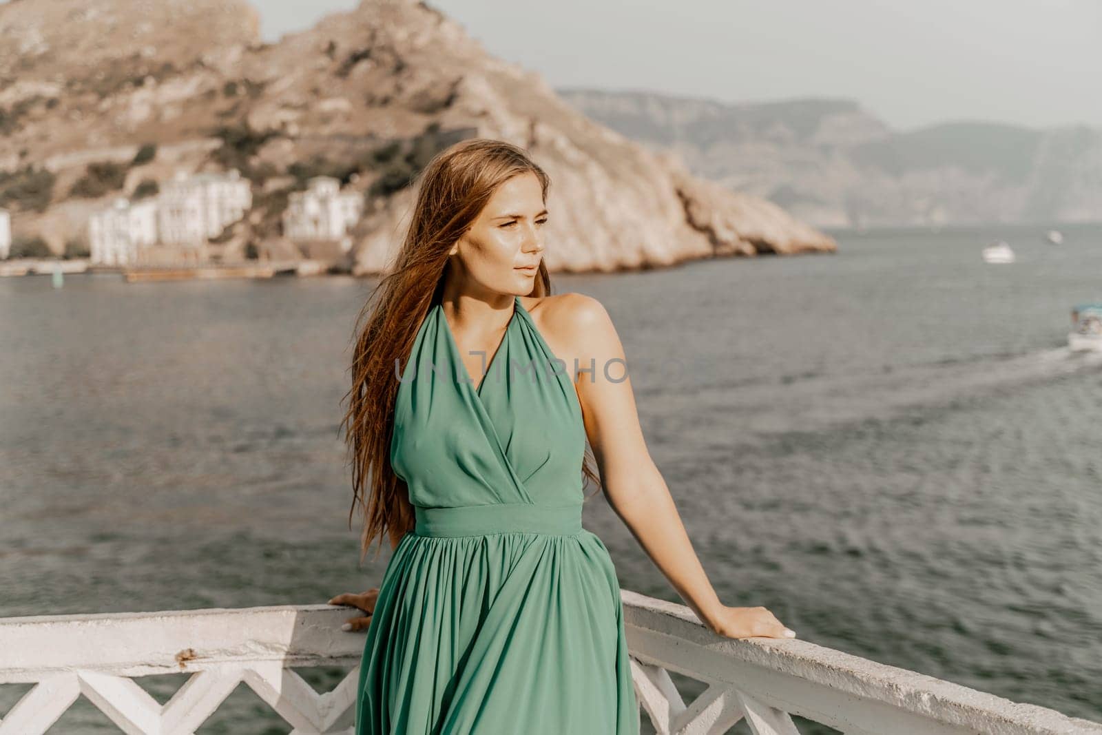 Woman sea green dress. Side view a happy woman with long hair in a long mint dress posing on a beach with calm sea bokeh lights on sunny day. Girl on the nature on blue sky background