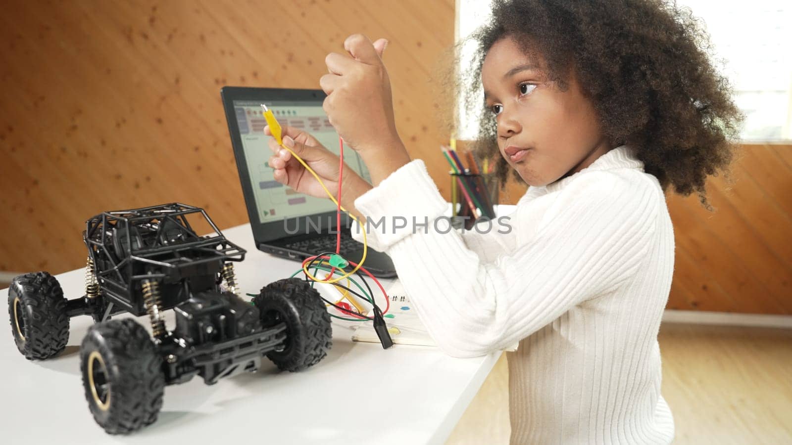 African girl build robotic car while using wires while using laptop. Erudition. by biancoblue