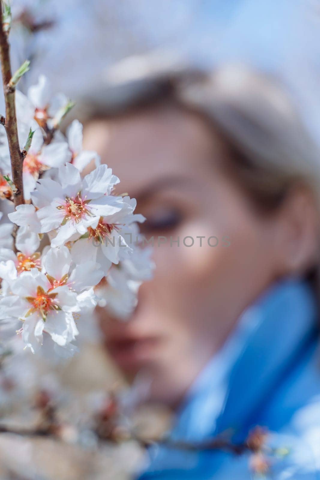 Portrait of young blonde woman in the blossom spring garden. Almond flowers blossoms.