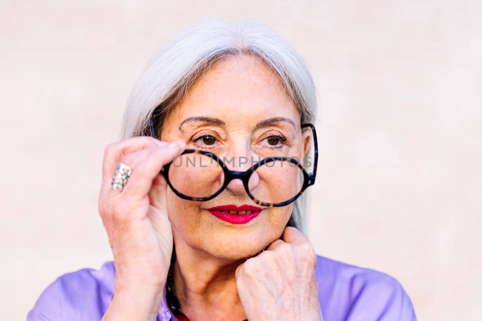 portrait of a beautiful senior woman taking off her glasses, concept of happiness of elderly people and active lifestyle