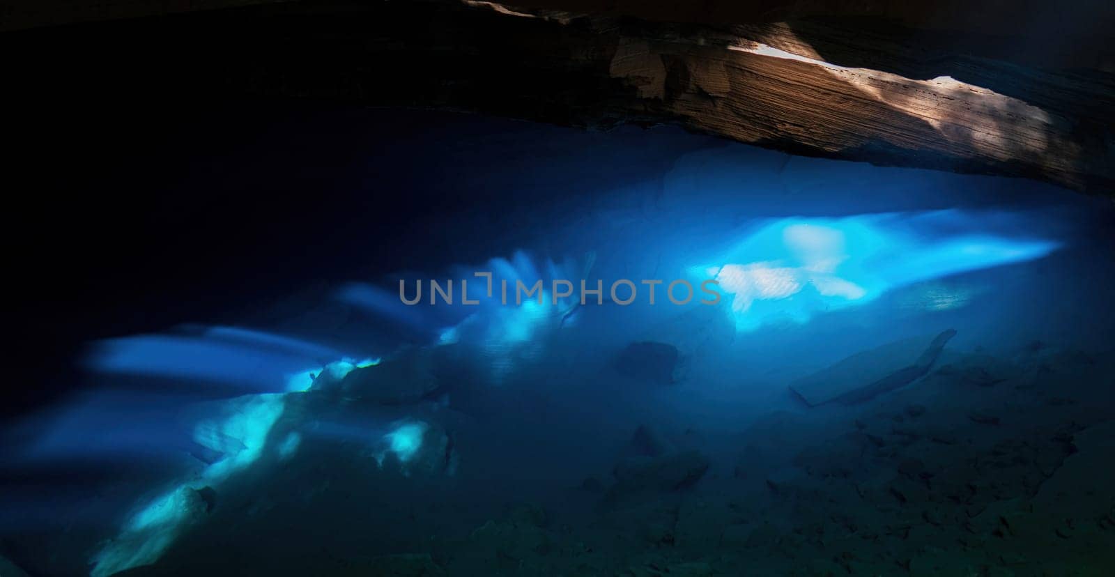 A serene underwater cave is illuminated by blue light, casting a magical glow and creating a tranquil atmosphere.