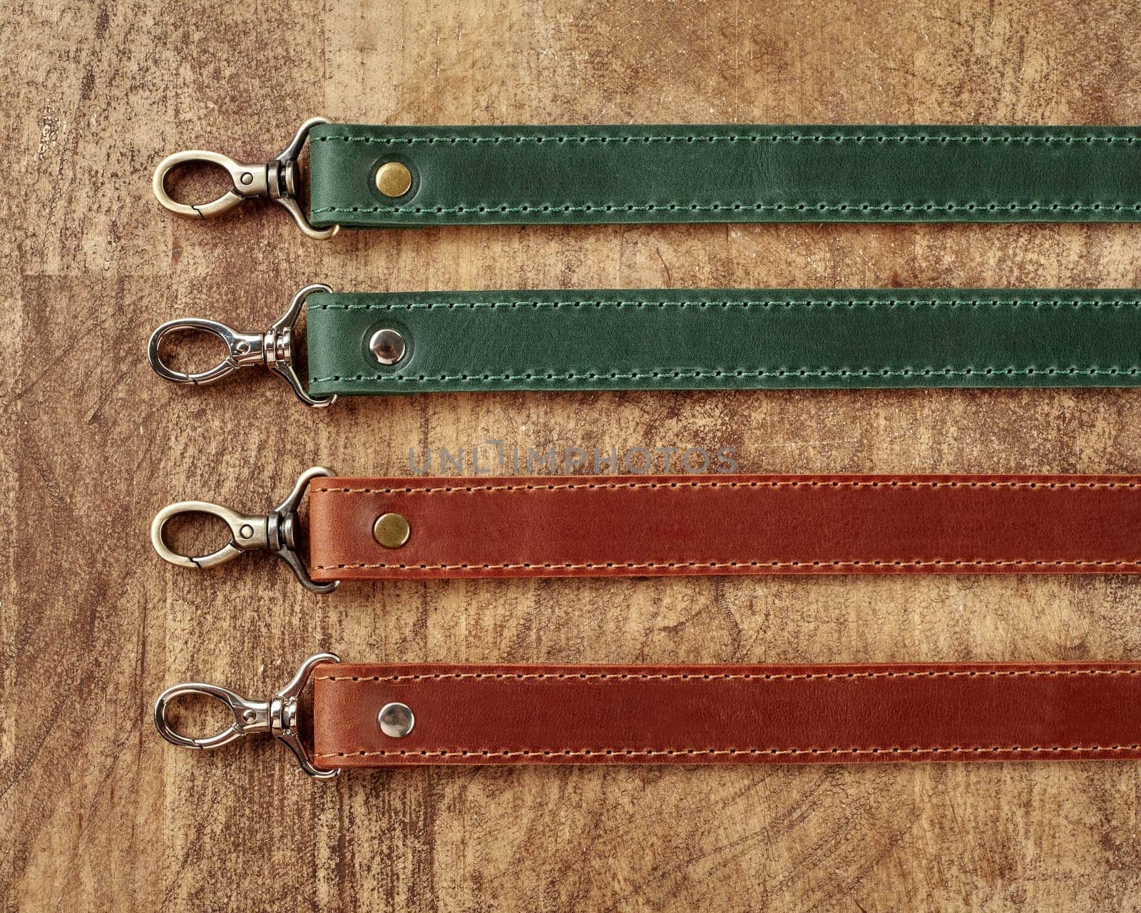 Collection of leather bag straps with carabiners on wooden surface by nazarovsergey