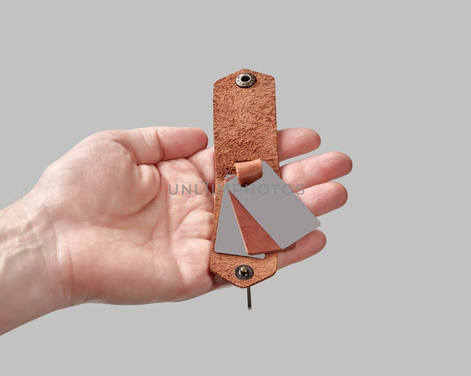 Bespoke brown leather key holder with printed family portrait in male hand by nazarovsergey