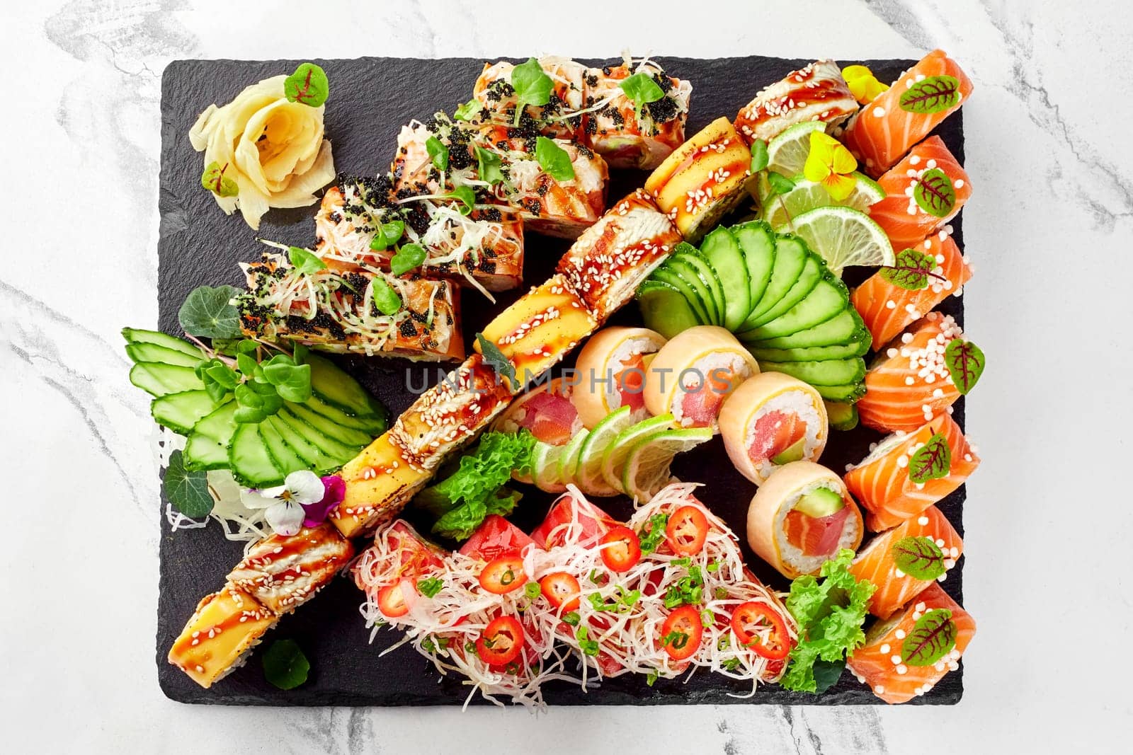 Top view of garnished salmon, eel and tuna sushi rolls on slate board by nazarovsergey