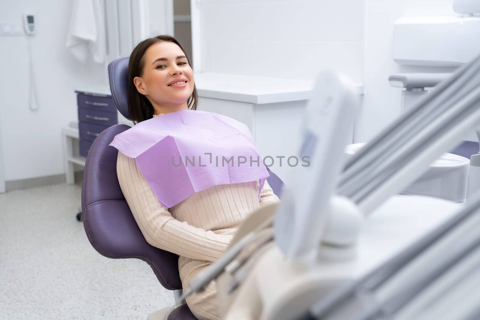 A smiling woman sitting in a dental chair and waiting for a checkup in the clinic.