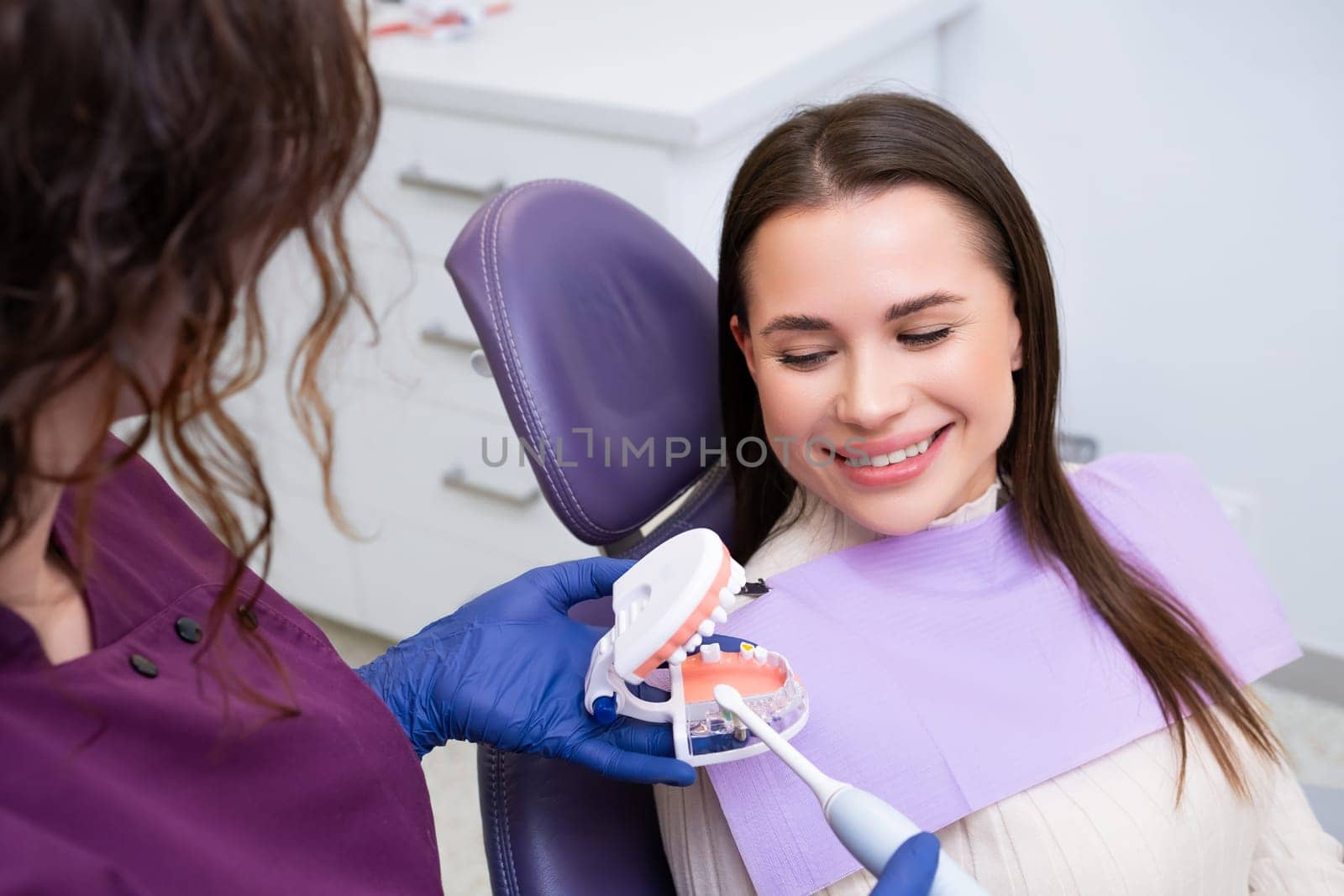 Dentist explains lady patient technique for brushing teeth by vladimka