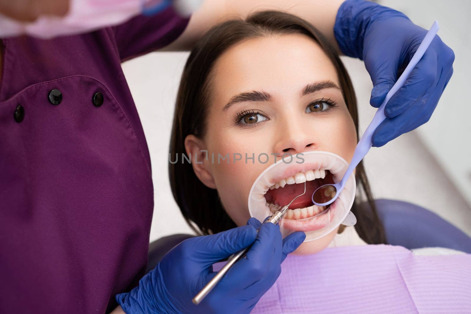 Female dentist blows air across teeth drying from saliva by vladimka