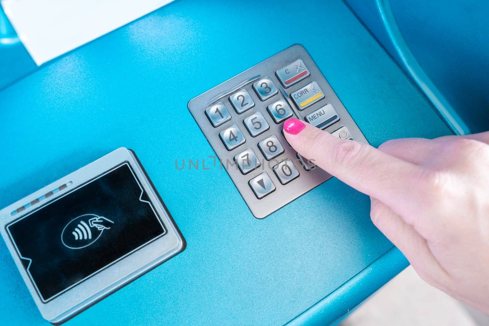 A female hand is using a communication device to press a button on an ATM machine, with a gesture of her finger. The office equipment has an electric blue font, enhancing the gadgets appearance