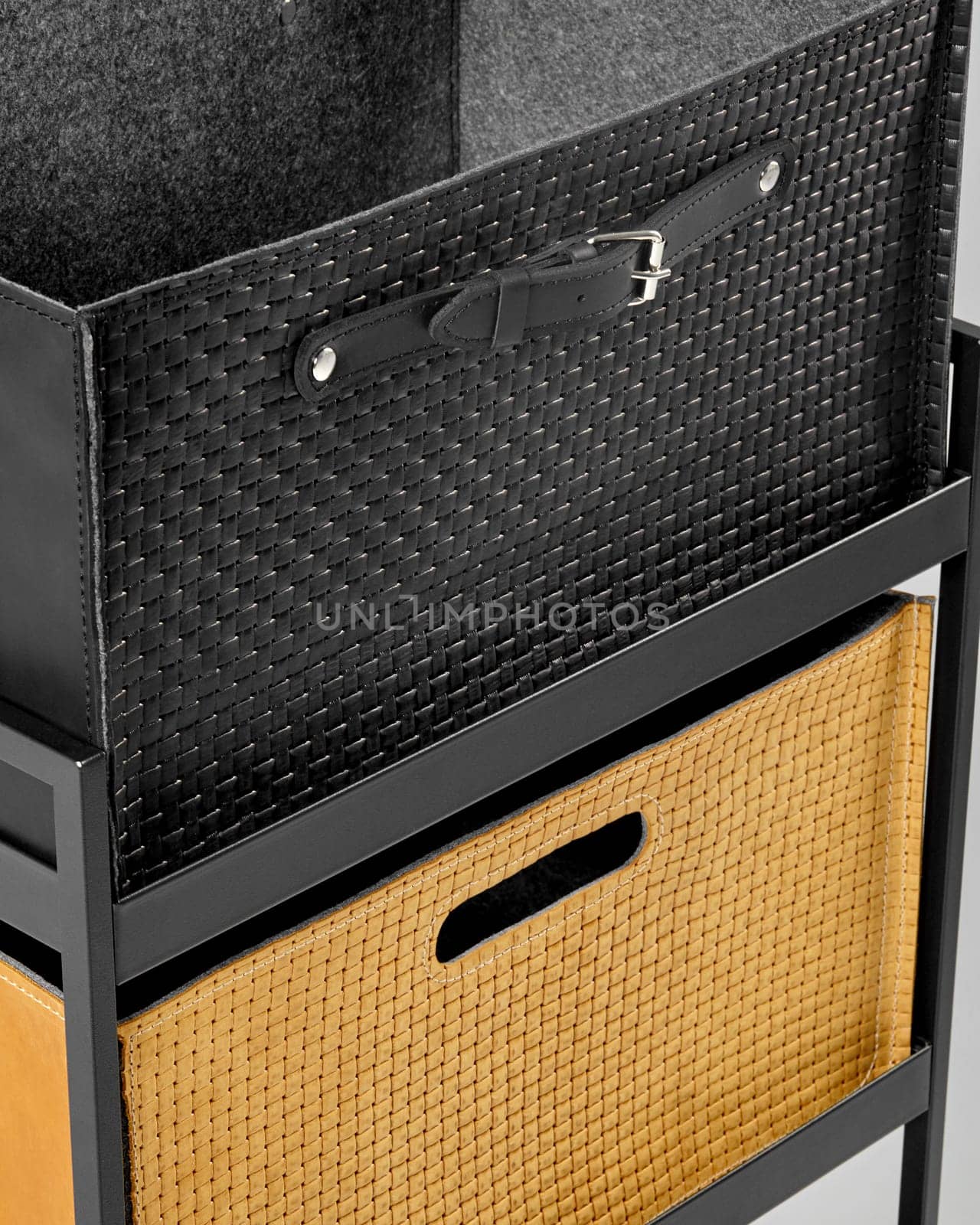 Closeup of black leather and tan suede storage woven boxes on metal shelf. Concept of elegant organization solutions for clutter-free and stylish home environment