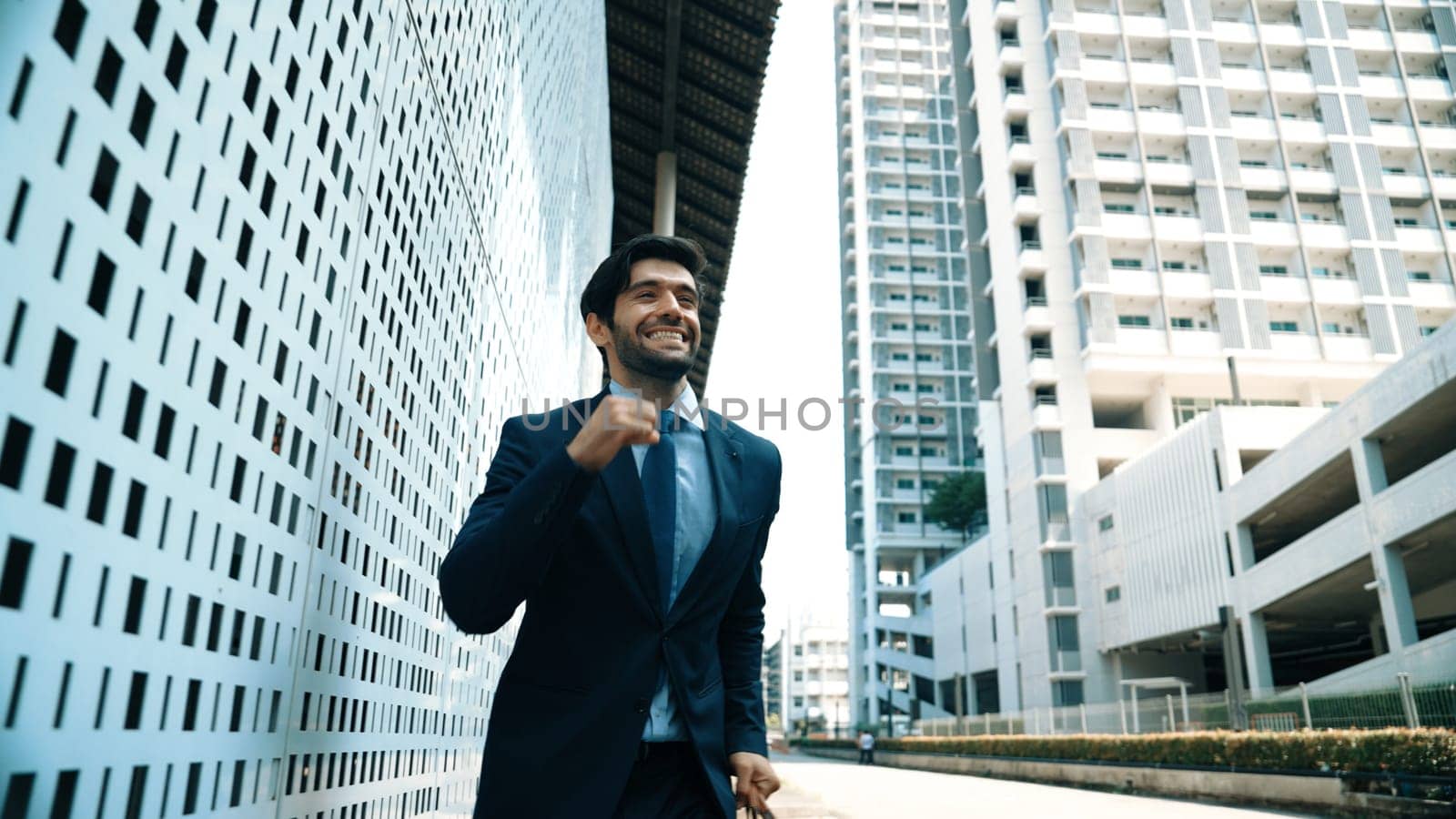 Skilled business man dancing with joyful while walking in city street. Project manger receive a good news, getting promotion, getting a successful job while express feeling of overjoy. Exultant.