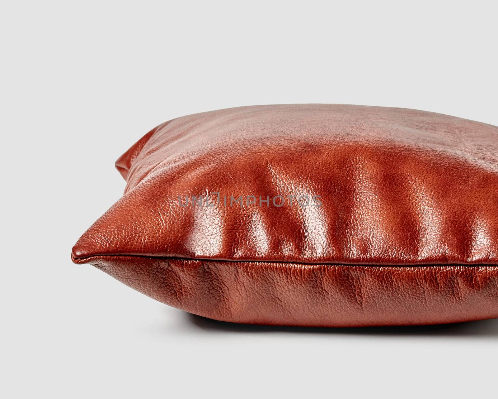 Artisanal sofa pillow of copper colored leather on white background by nazarovsergey