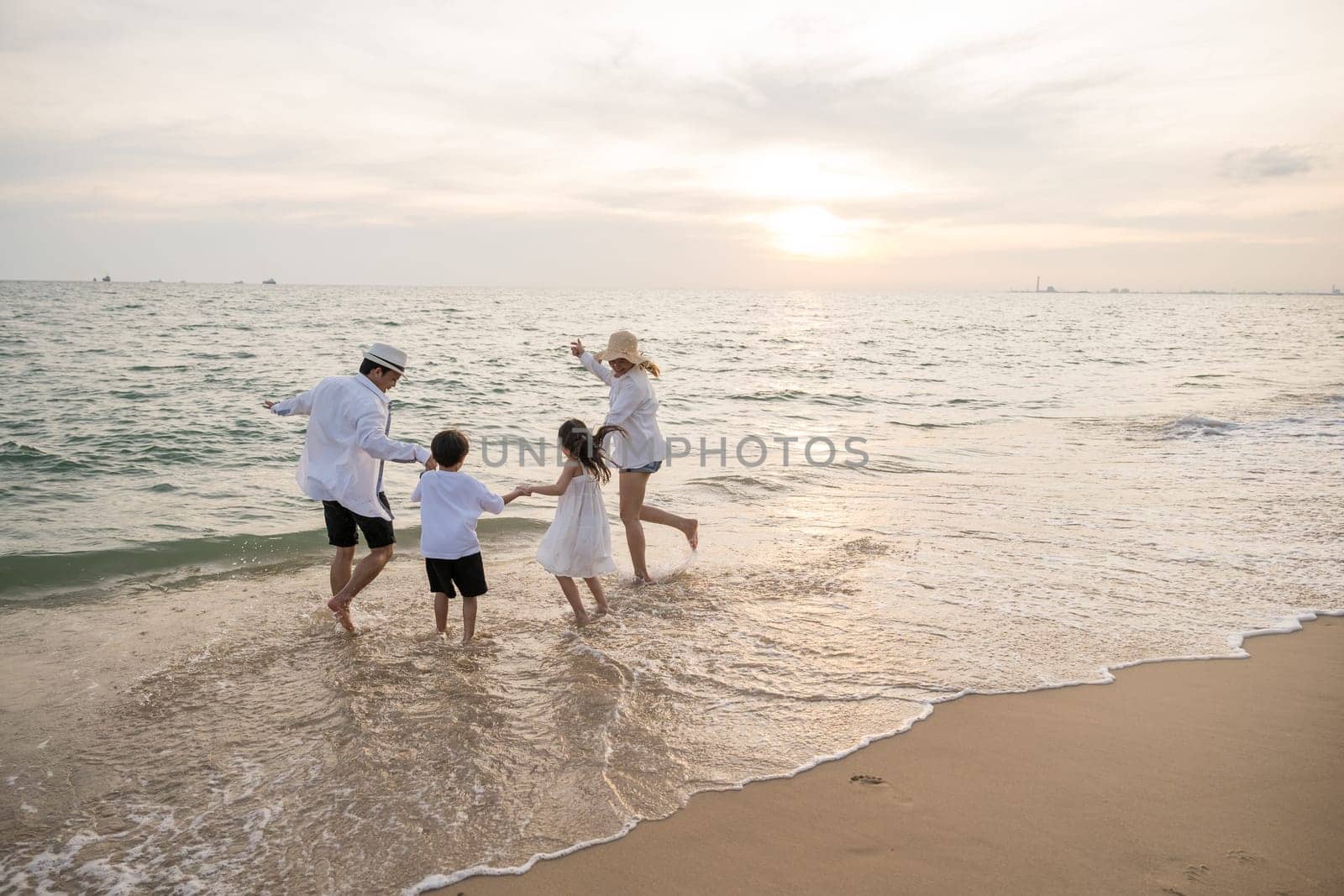 Captivating sunset on beach where parents playfully interact with their kid during holiday. essence of summer vacation is captured joyful family including happy mother father and children run in ocean by Sorapop
