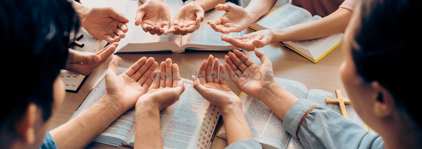 Cropped image of diversity people hand praying together at wooden church on bible book. Group of believer hold hand together faithfully. Concept of hope, religion, faith, god blessing. Burgeoning.