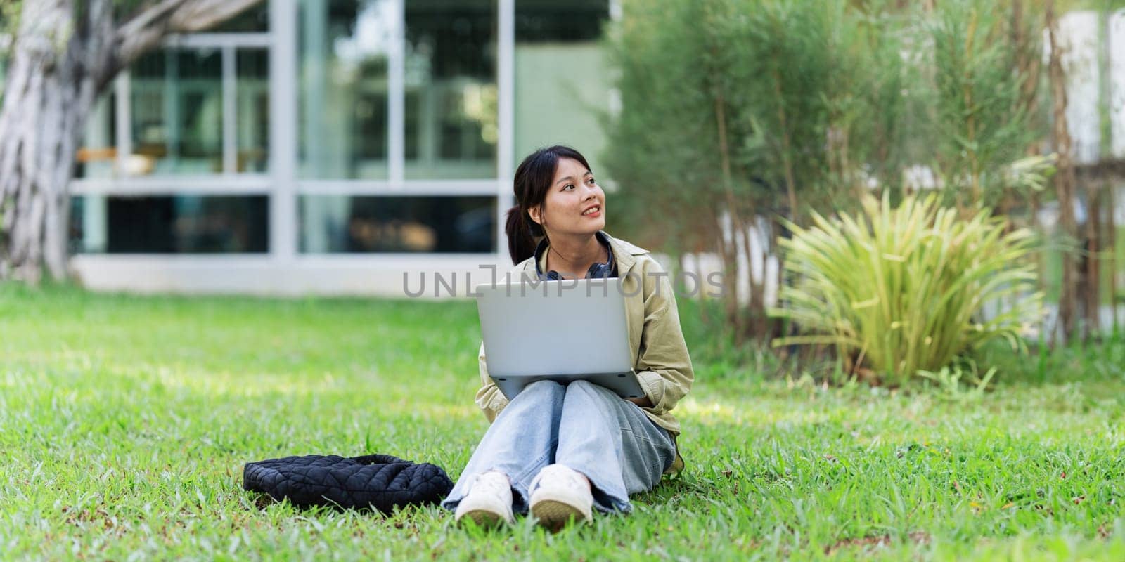 Young Asian student sitting and using laptop at university before class room. education, back to school concept by itchaznong