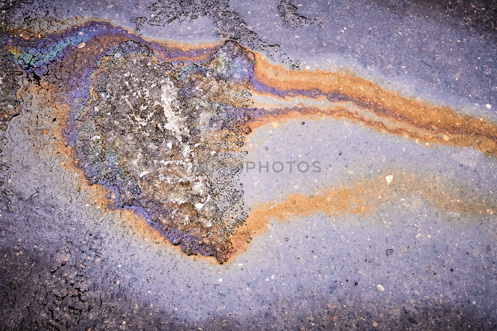 A bright spot of oil or gasoline splash on the asphalt after the snow melts.