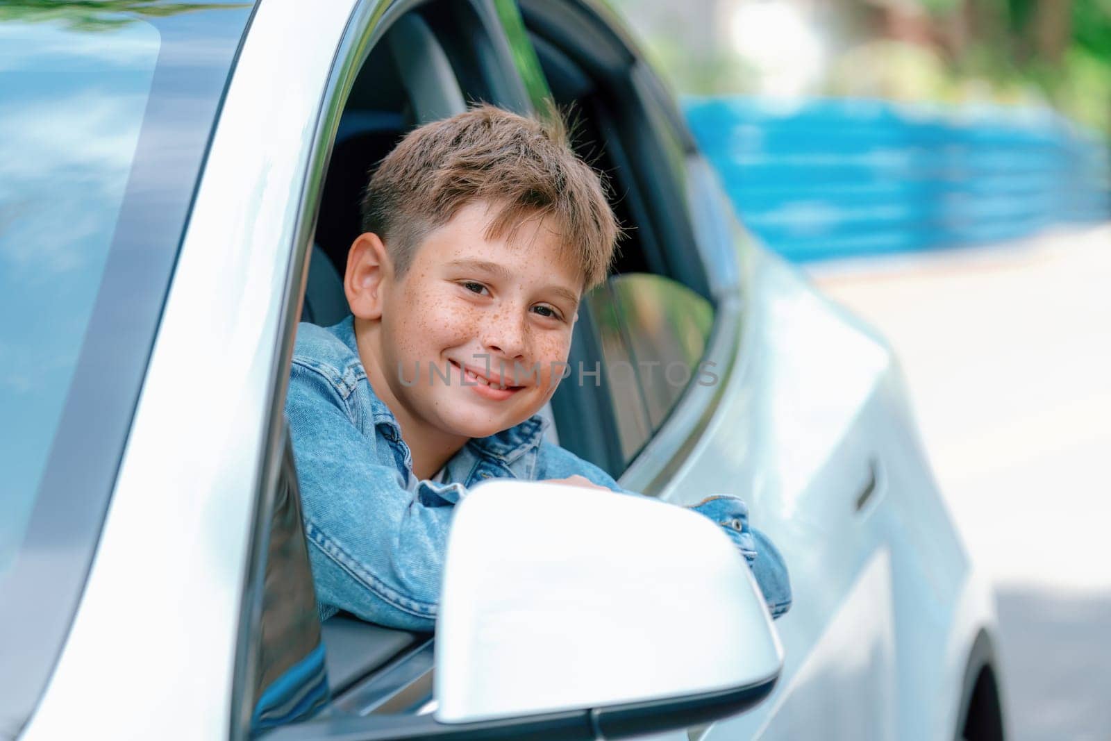 Excited and happy young little boy with smile on his face show up on car window while driving, playful and cheerful expression while on the road trip traveling by car during summertime. Perpetual