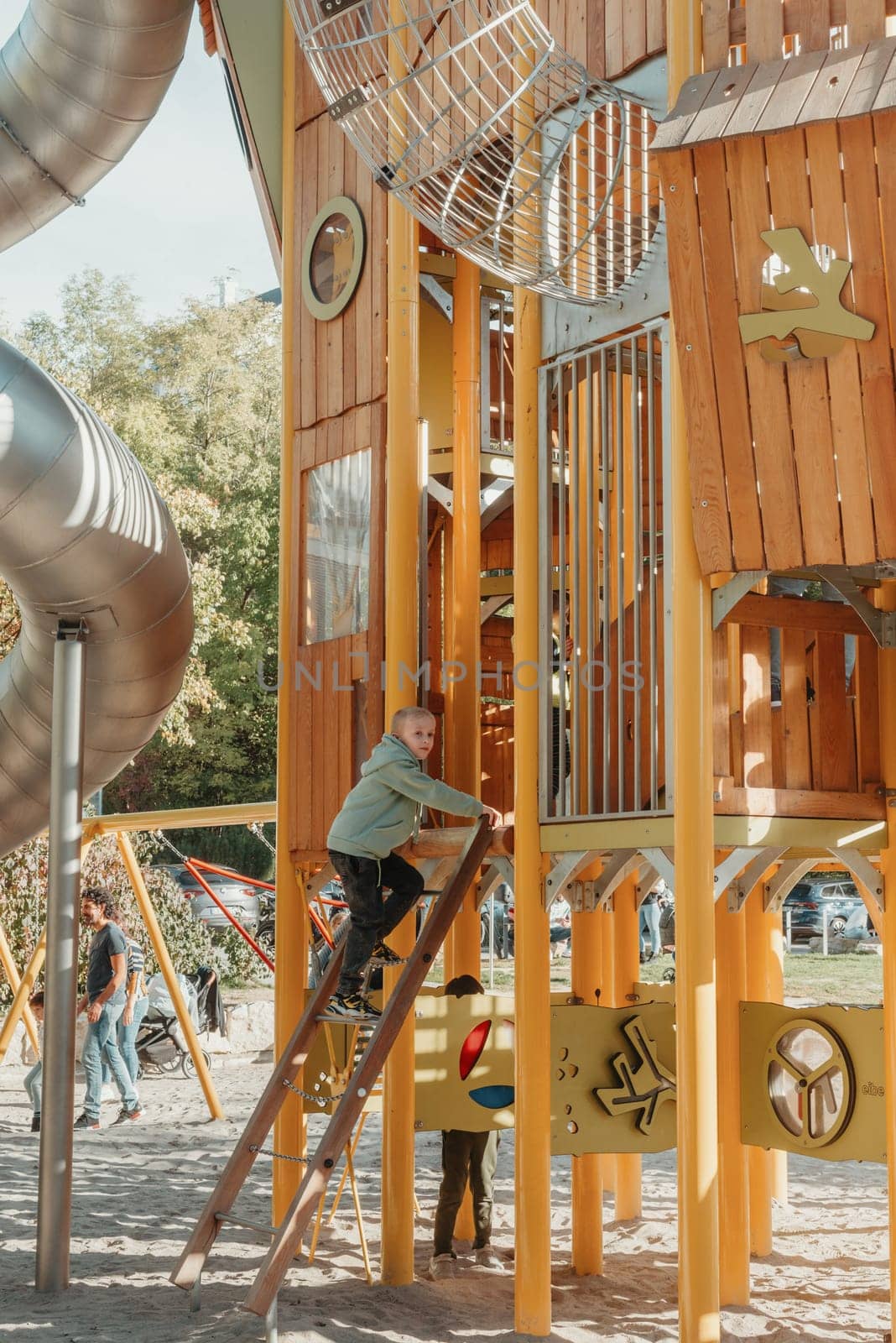 boy playing on the children's playground, a boy on a playground in the park climbs up a climbing wall. Kids having fun and sliding on outdoor playground. Kids Enjoying. A child climbs up an alpine grid in a park on a playground on a hot summer day. children's playground in a public park, entertainment and recreation for children, mountaineering training.