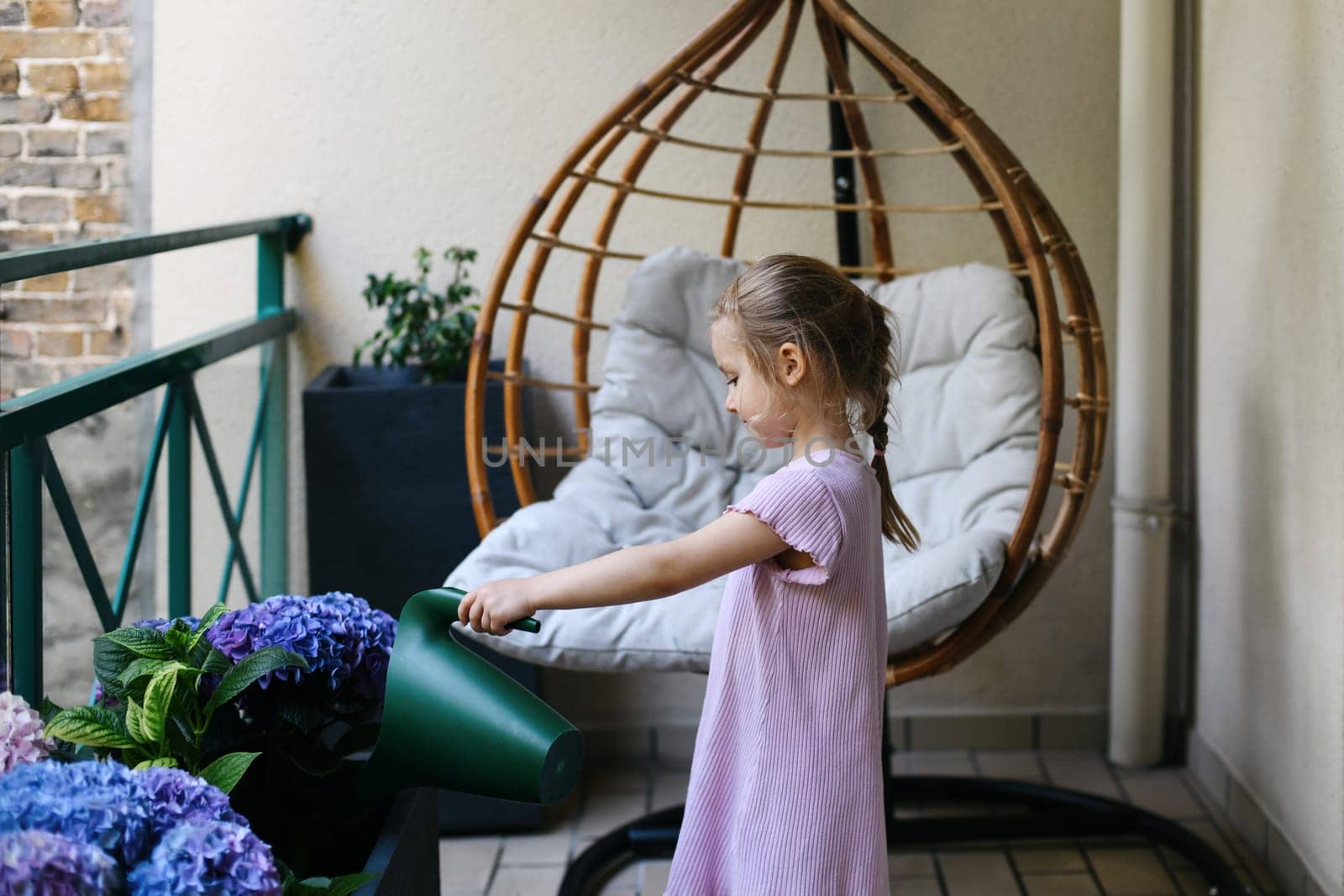 Girl watering hydrangeas on the balcony