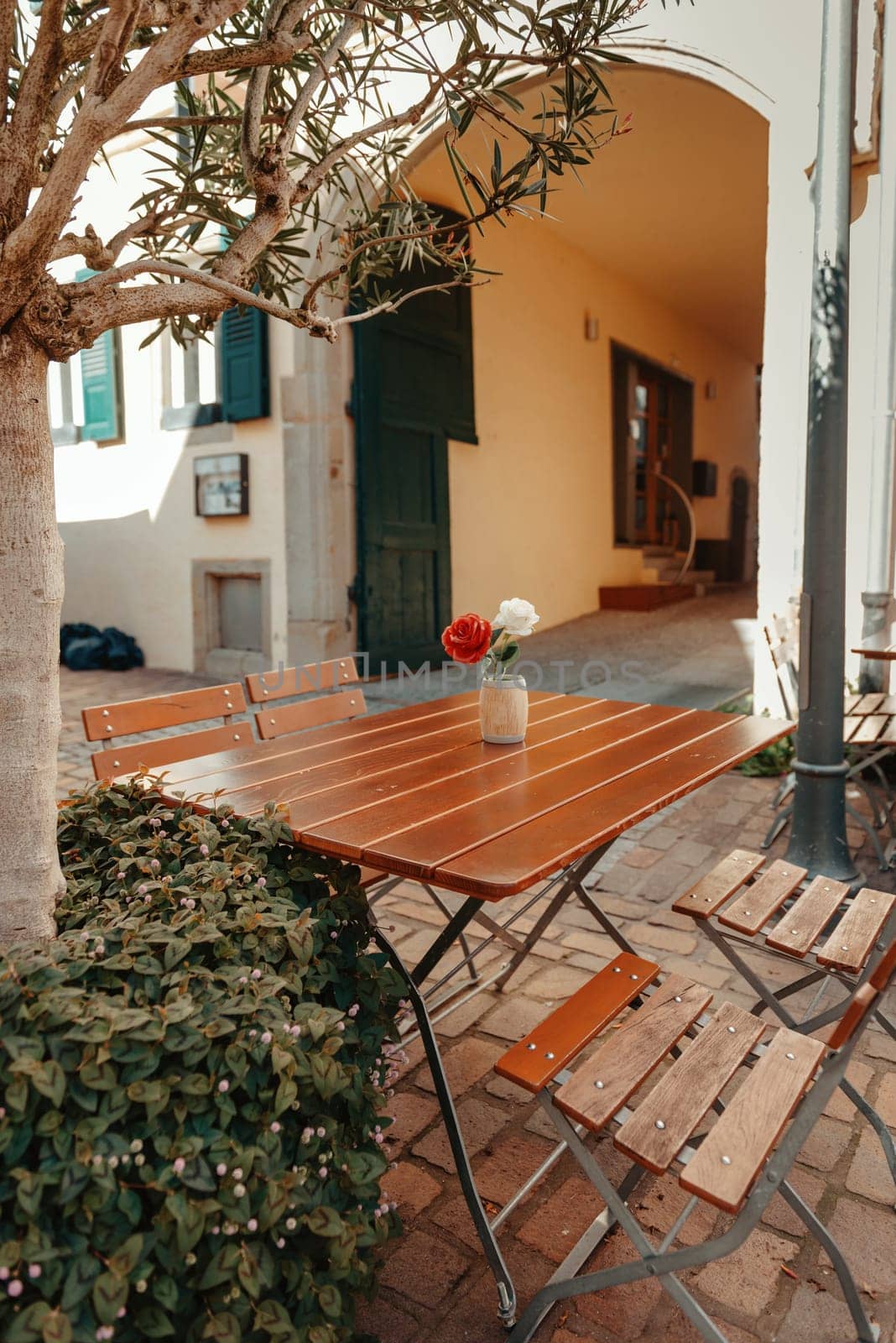 Empty cafe terrace with white table and chair. exterior of the cafe restaurant. interior Street cafe. Cozy street with flowers and French-style cafe table. Decor facade of coffeehouse with bike. Table on a summer terrace with cake and teapot. Garden table and chairs