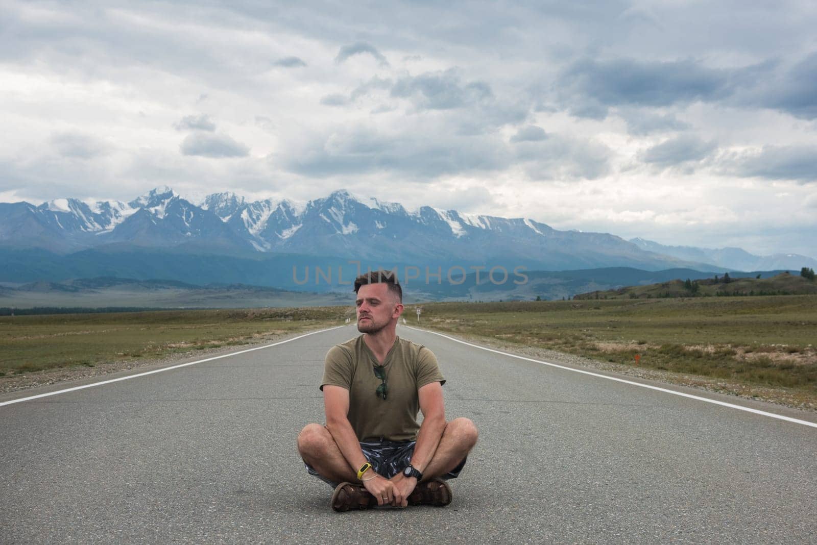 A young man sitting on the road in the Chuysky Tract area. Altai Republic, Russia.