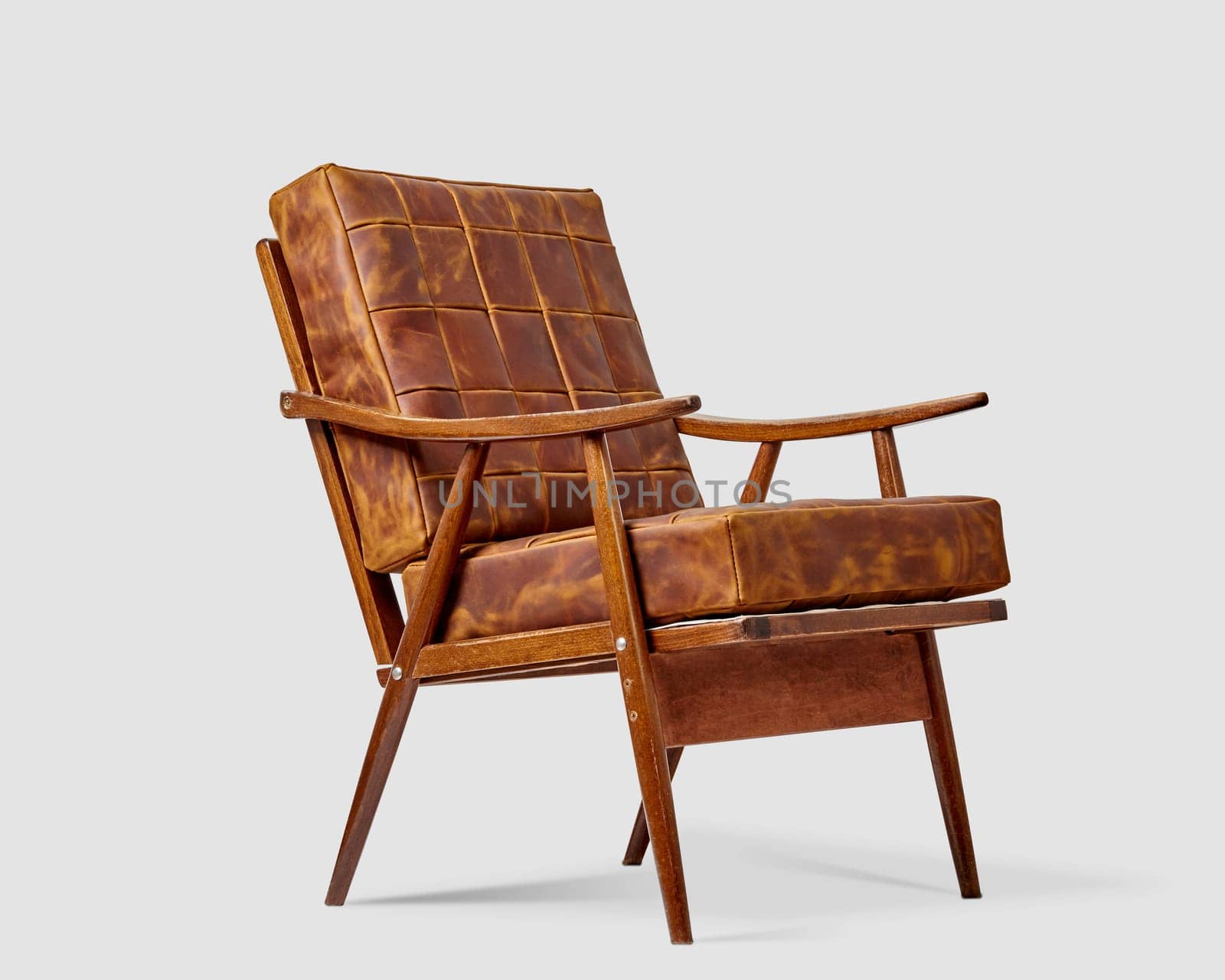 Vintage wooden armchair with soft brown patchwork leather cushions against white background. Artisanal furniture concept