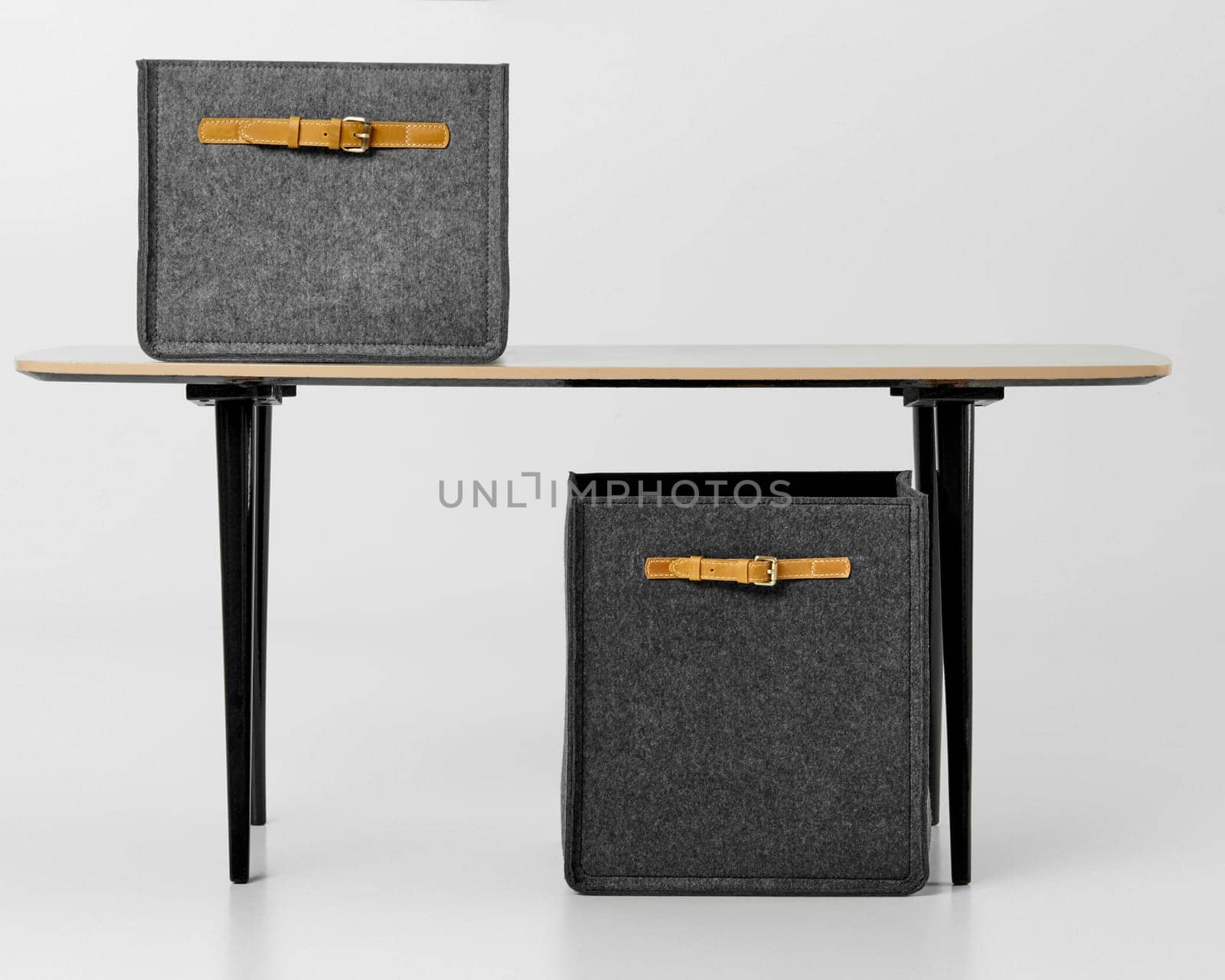 Contemporary office setup featuring modern grey felt storage boxes with tan leather handles on minimalist desk on white background