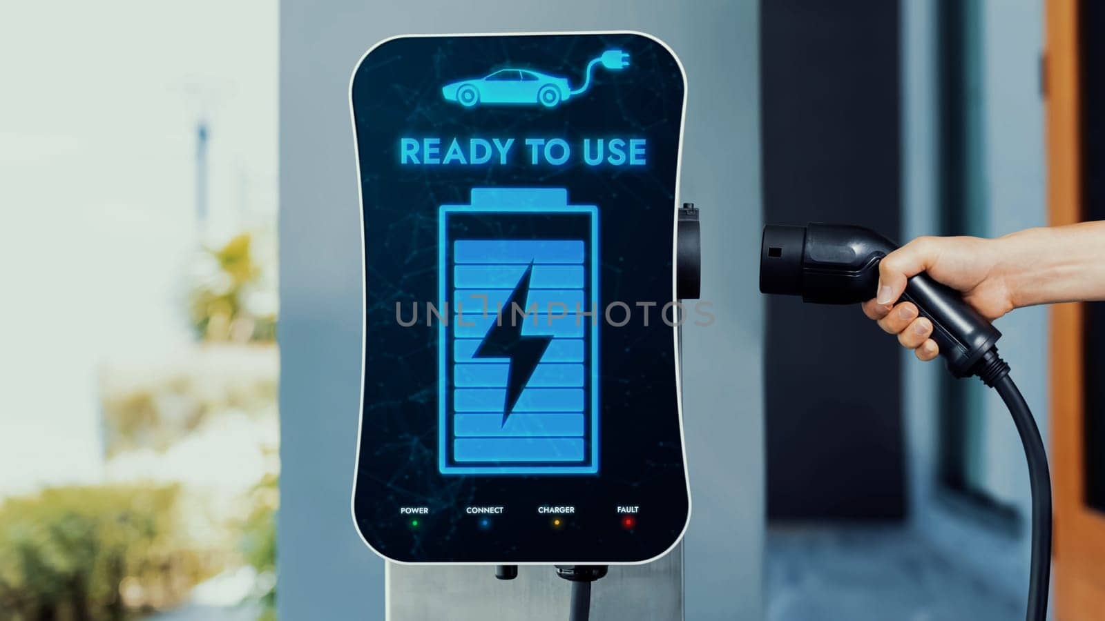 Home electric charging station showing battery status interface on screen with hand holding EV charger. Technological advancement of alternative energy sustainability and EV car. Peruse