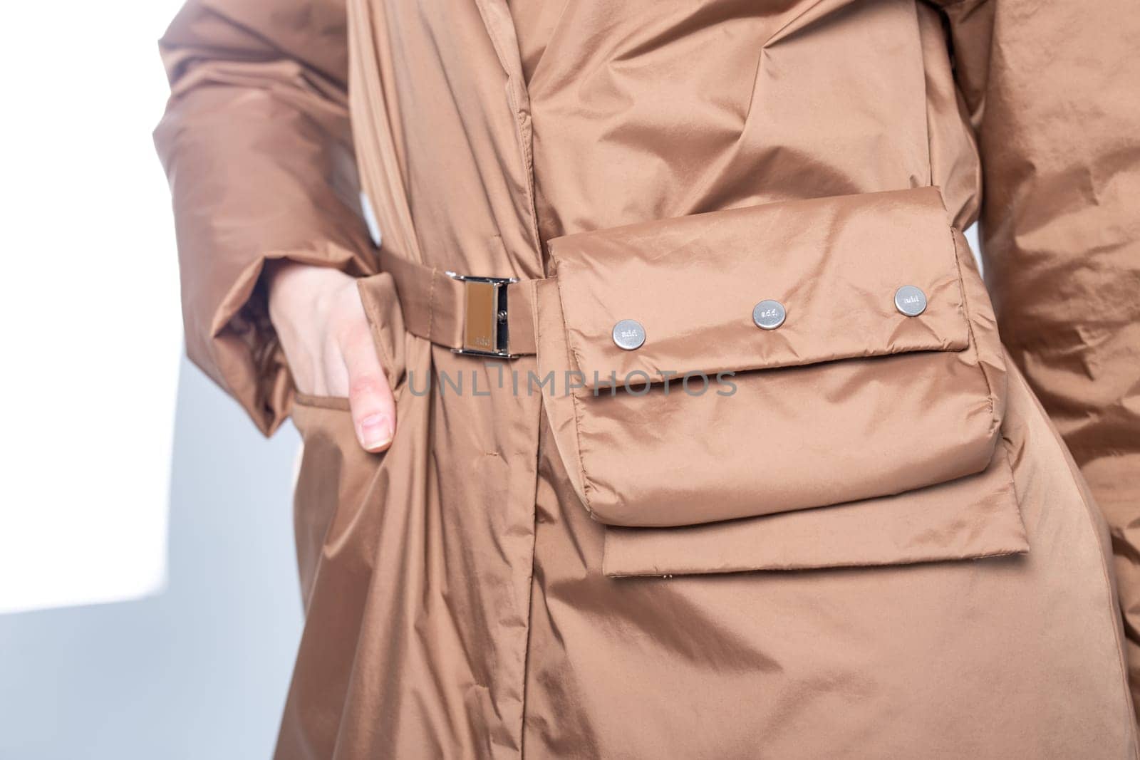 Woman wearing stylish brown trench coat with pockets and belt by Pukhovskiy