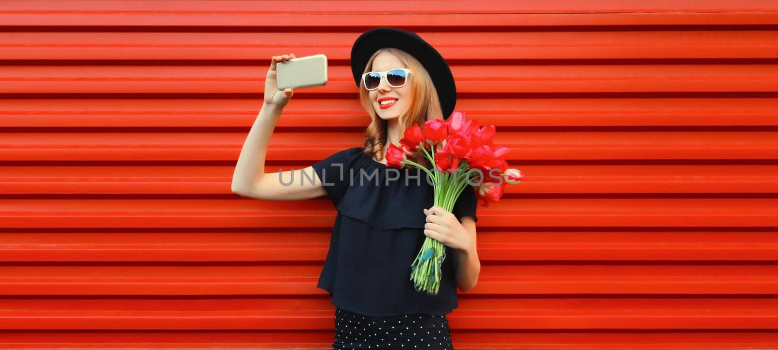 Beautiful young woman taking selfie with smartphone holding bouquet of red rose flowers by Rohappy