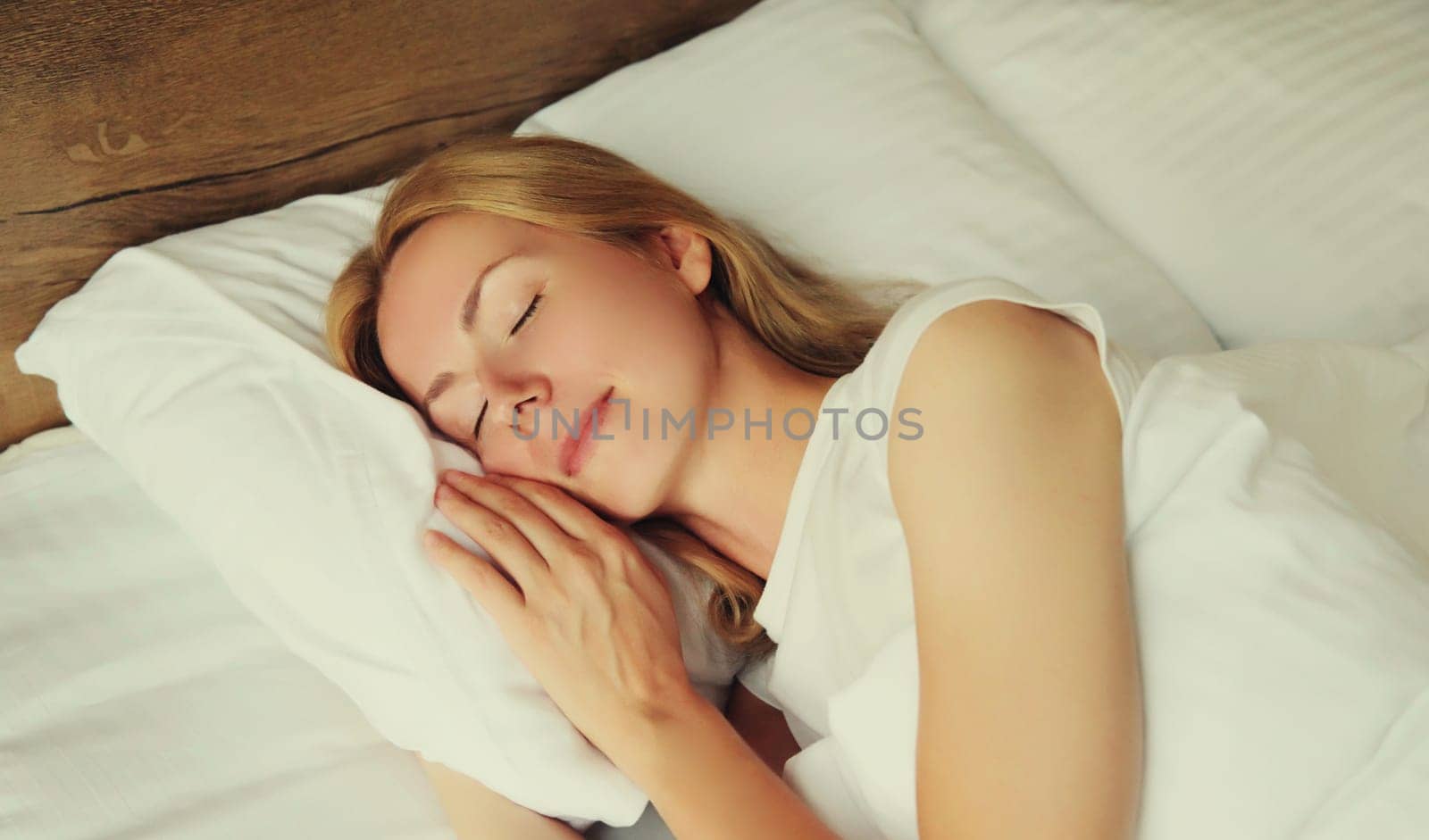 Young woman sleeping lying in bed on white soft comfortable pillow in bedroom at home
