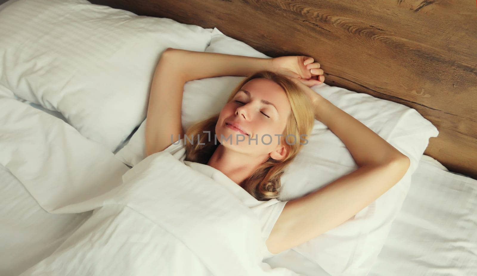 Young woman sleeping lying in bed on white soft comfortable pillow in bedroom at home