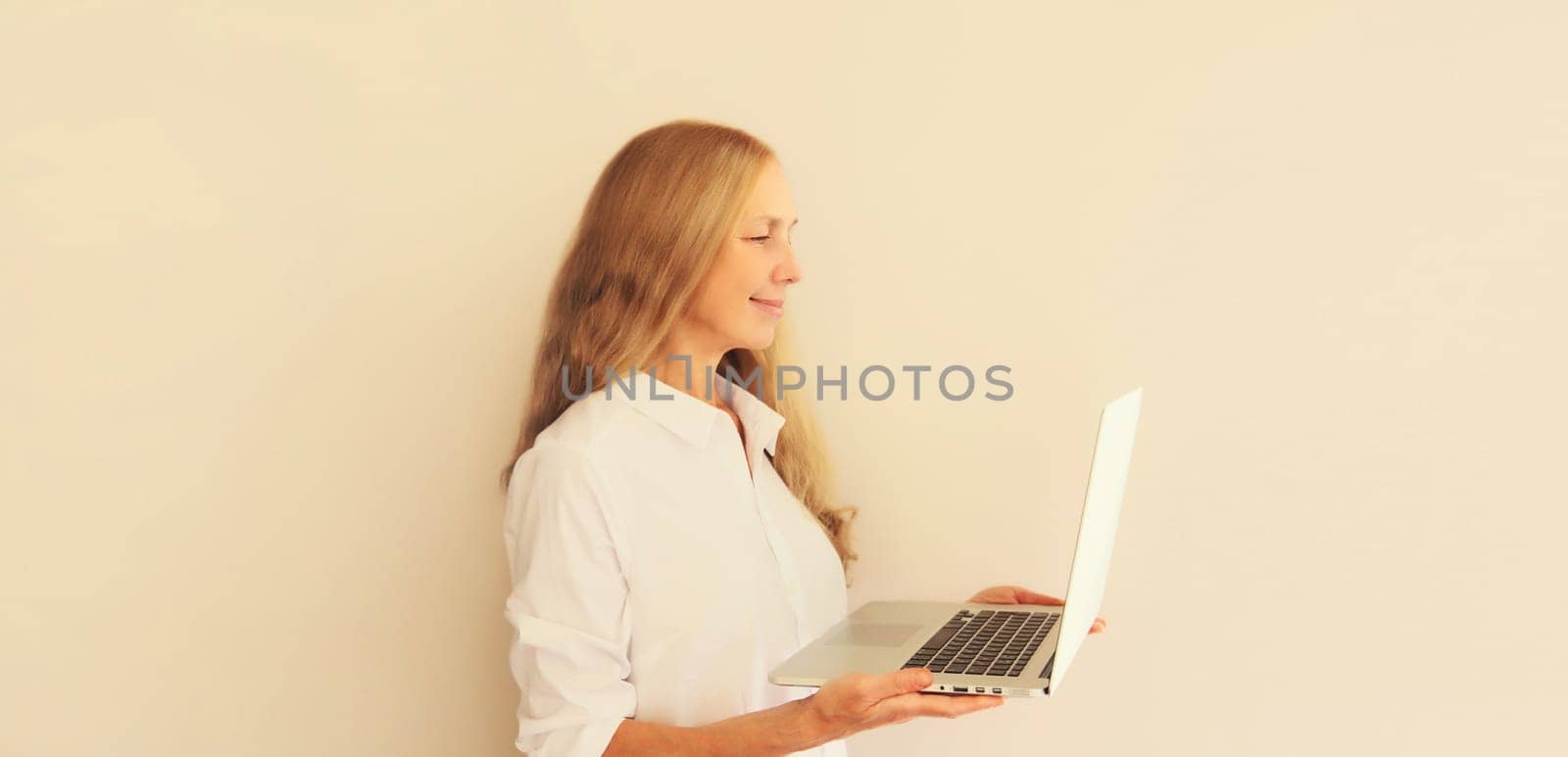 Happy caucasian middle-aged woman working with laptop at home