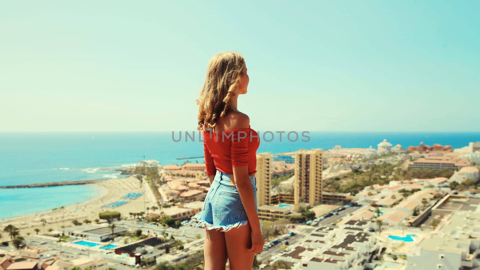 Summer vacation, beautiful young woman tourist on top of the mountain looking around the city in Tenerife, Canary Islands, Spain. Aerial top view.