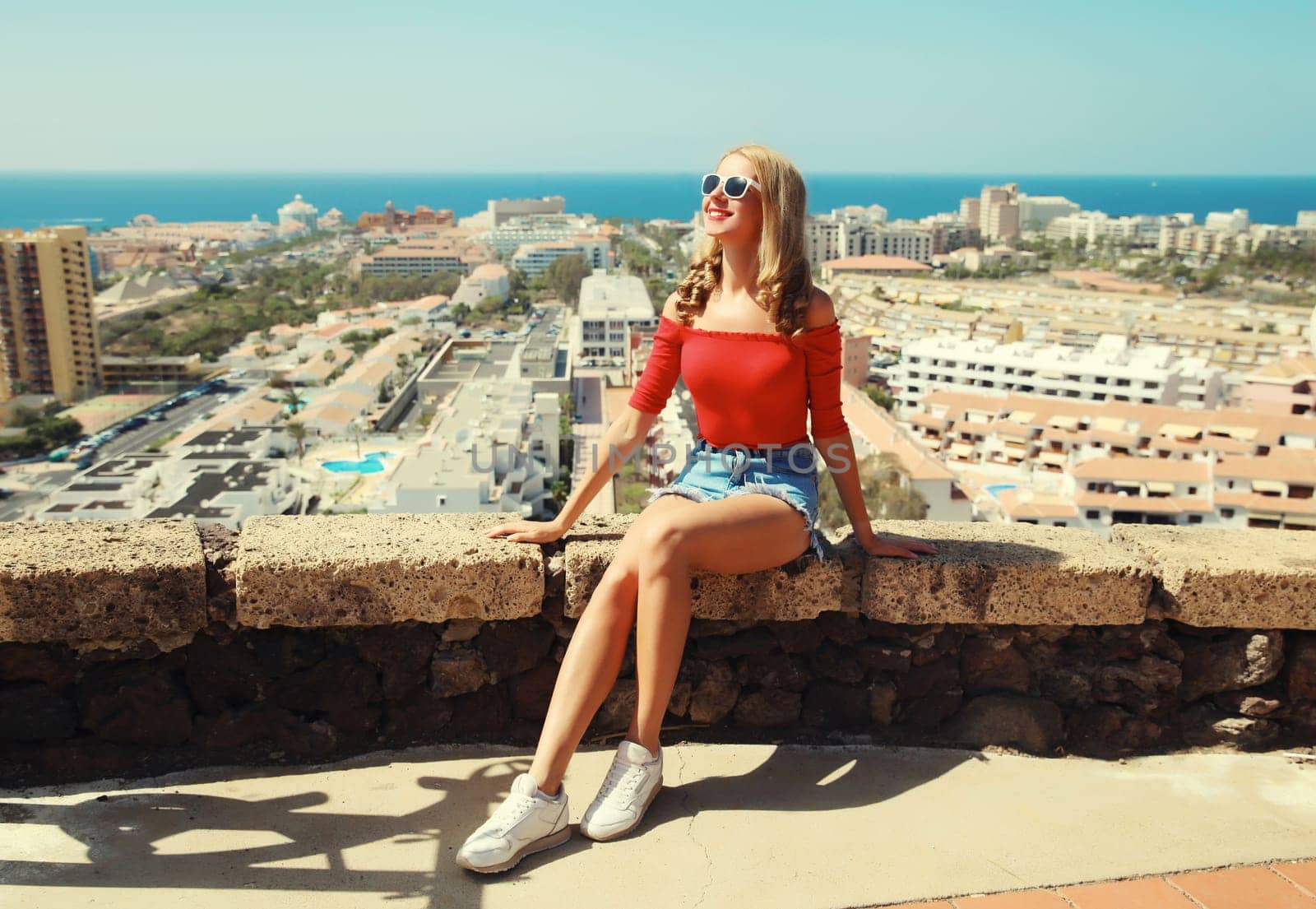 Summer vacation, beautiful young woman tourist on top of the mountain looking around the city in Tenerife, Canary Islands, Spain. Aerial top view.