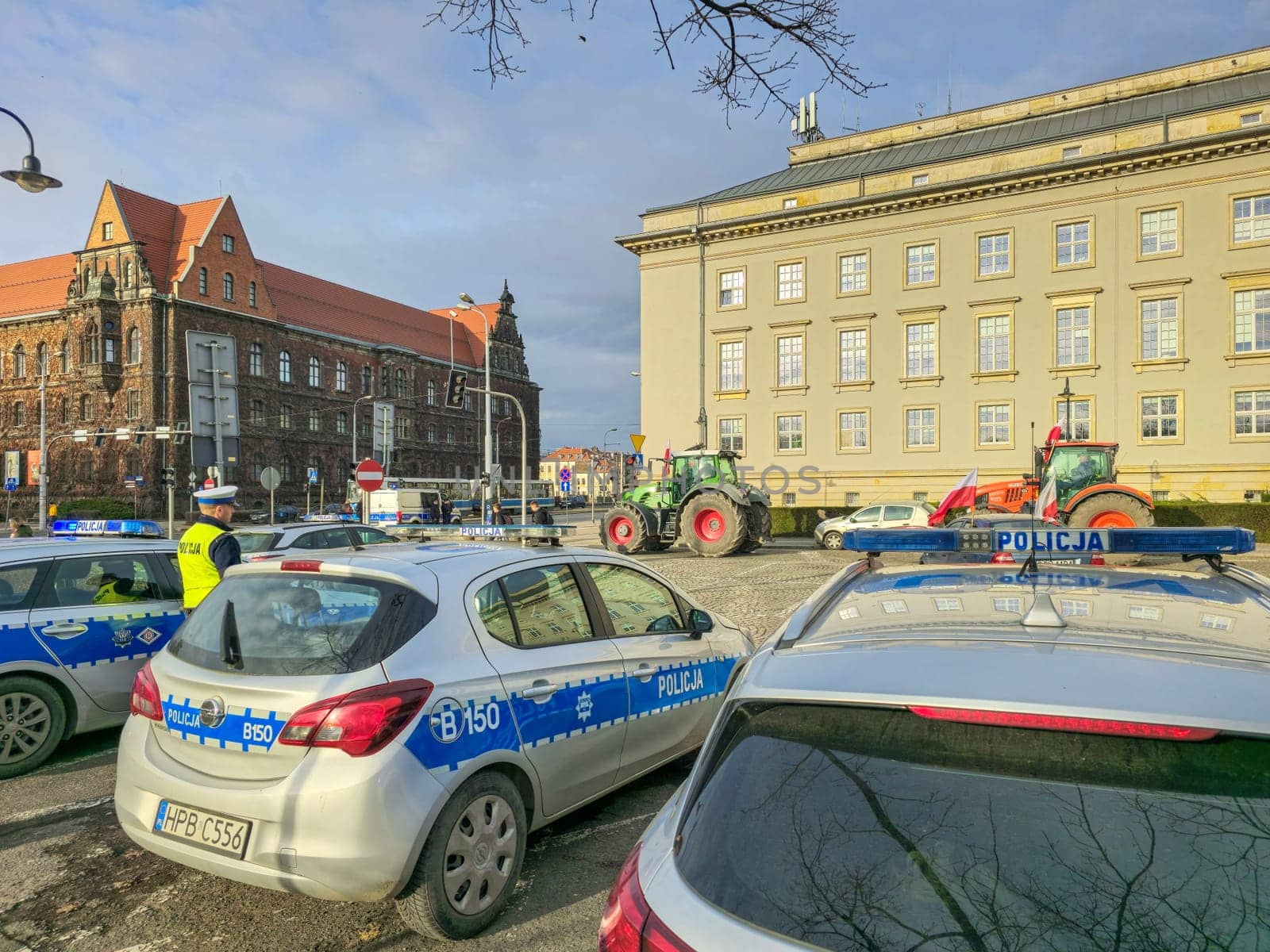 Wroclaw, Poland, February 15, 2024: Farmers protest against anti-farmer policy. Several police cars are parked in front of a large building. High quality