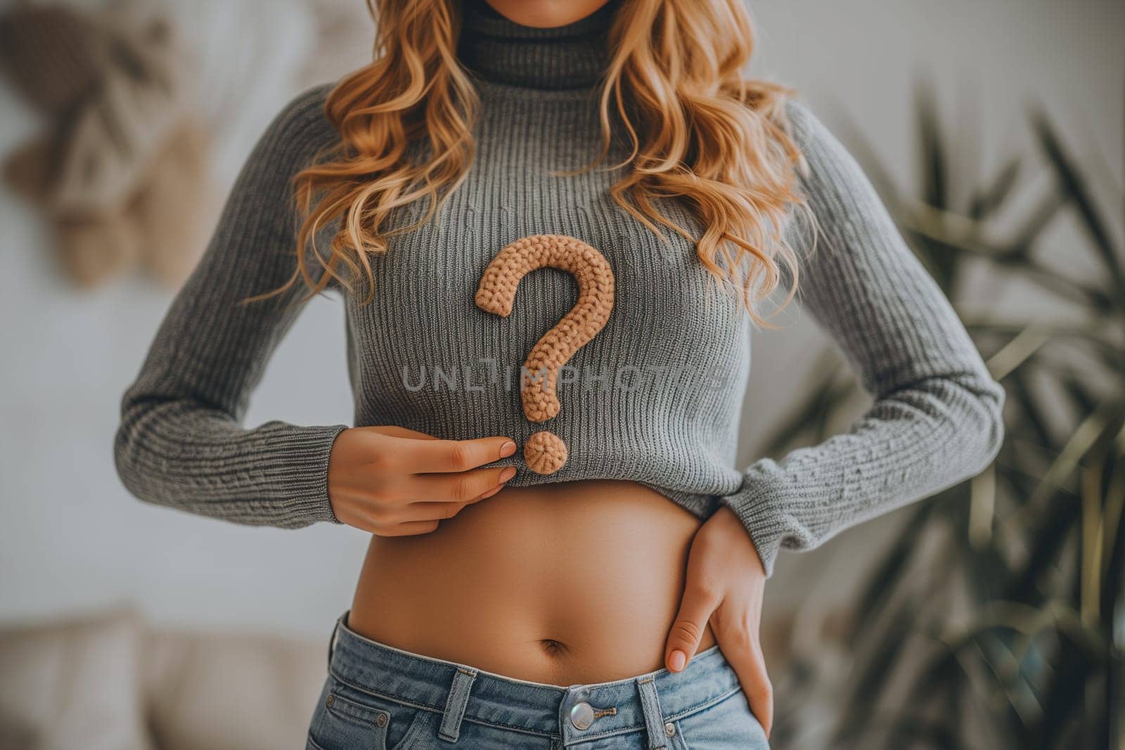 Woman holding question mark over her abdomen.