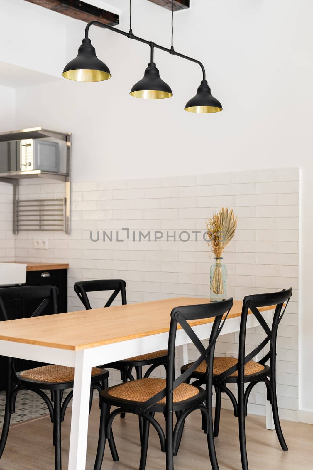 Fragment of a stylish living room with chairs and a dining table in a loft style with dark lamps in a modern apartment. Unique design concept for a young family in a new home by apavlin