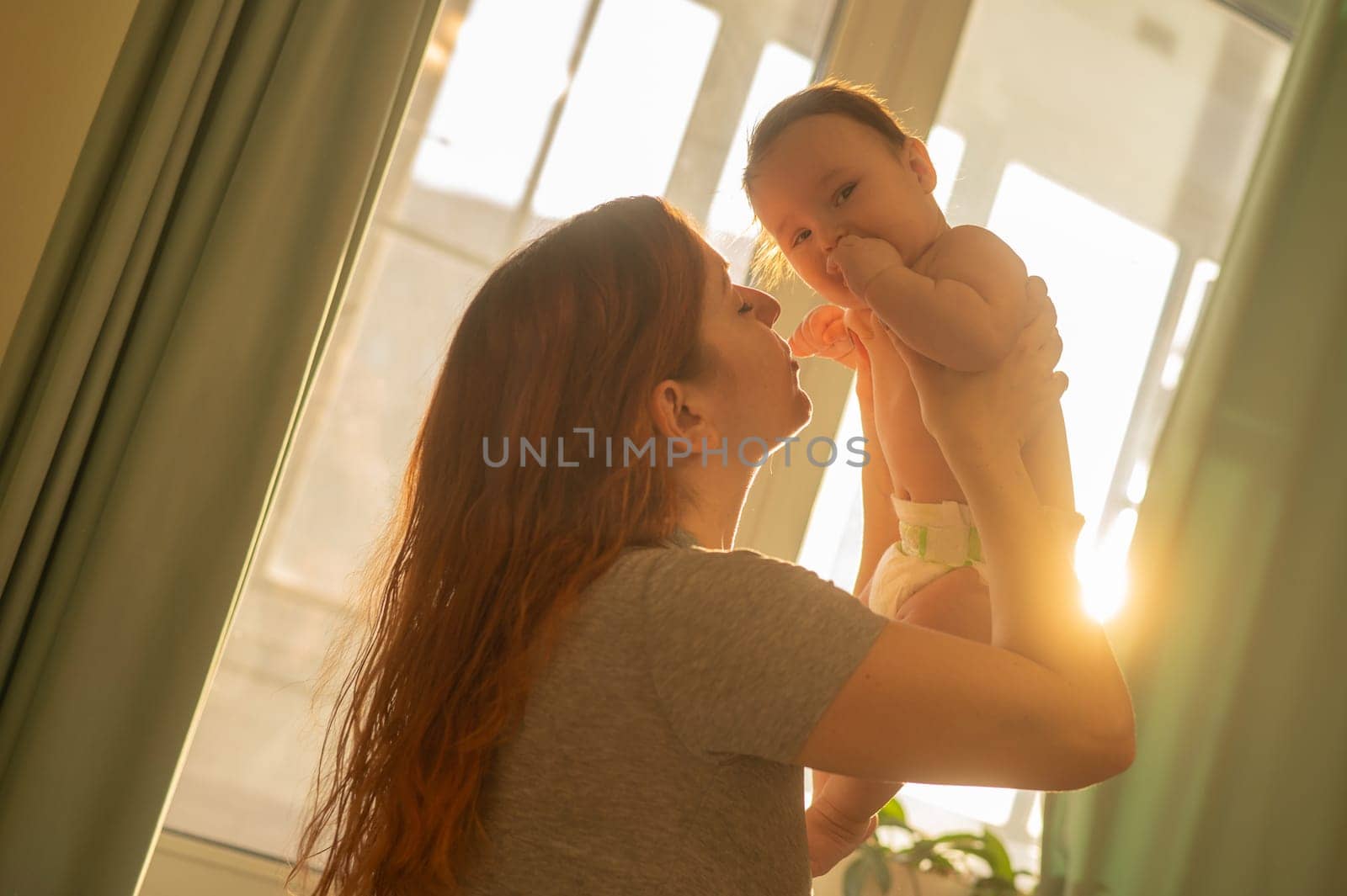 Caucasian woman gently lifts up her newborn son