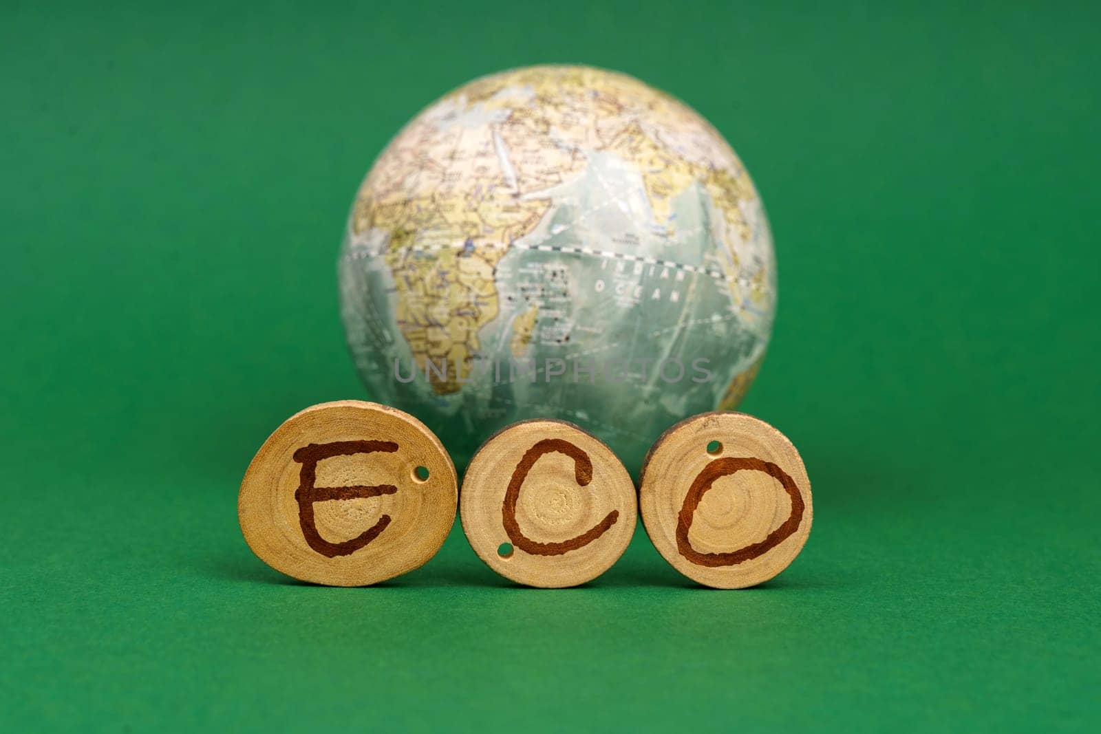 Ecological concept. On a green background there is an Earth globe and wooden roundels with the inscription - ECO