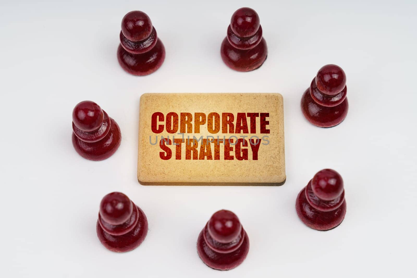 Business concept. On a white background, pawns stand around a sign with the inscription - Corporate Strategy