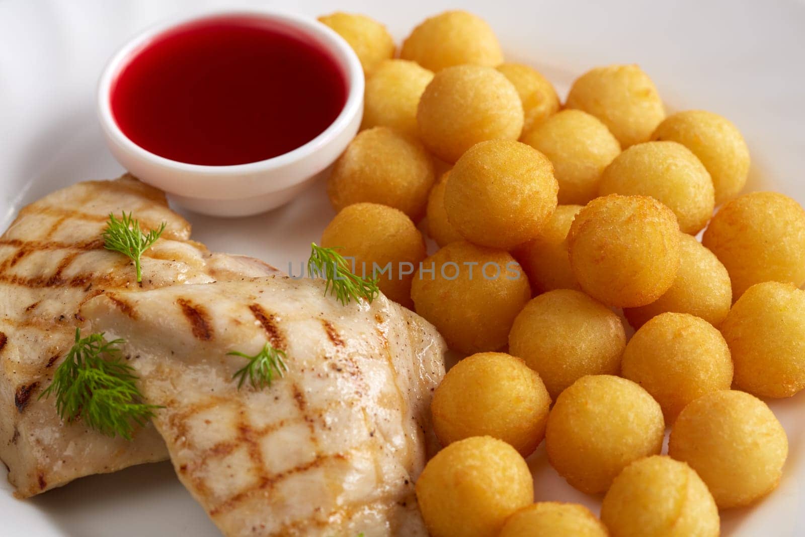 Close-up of grilled meat, cheese balls and cranberry sauce