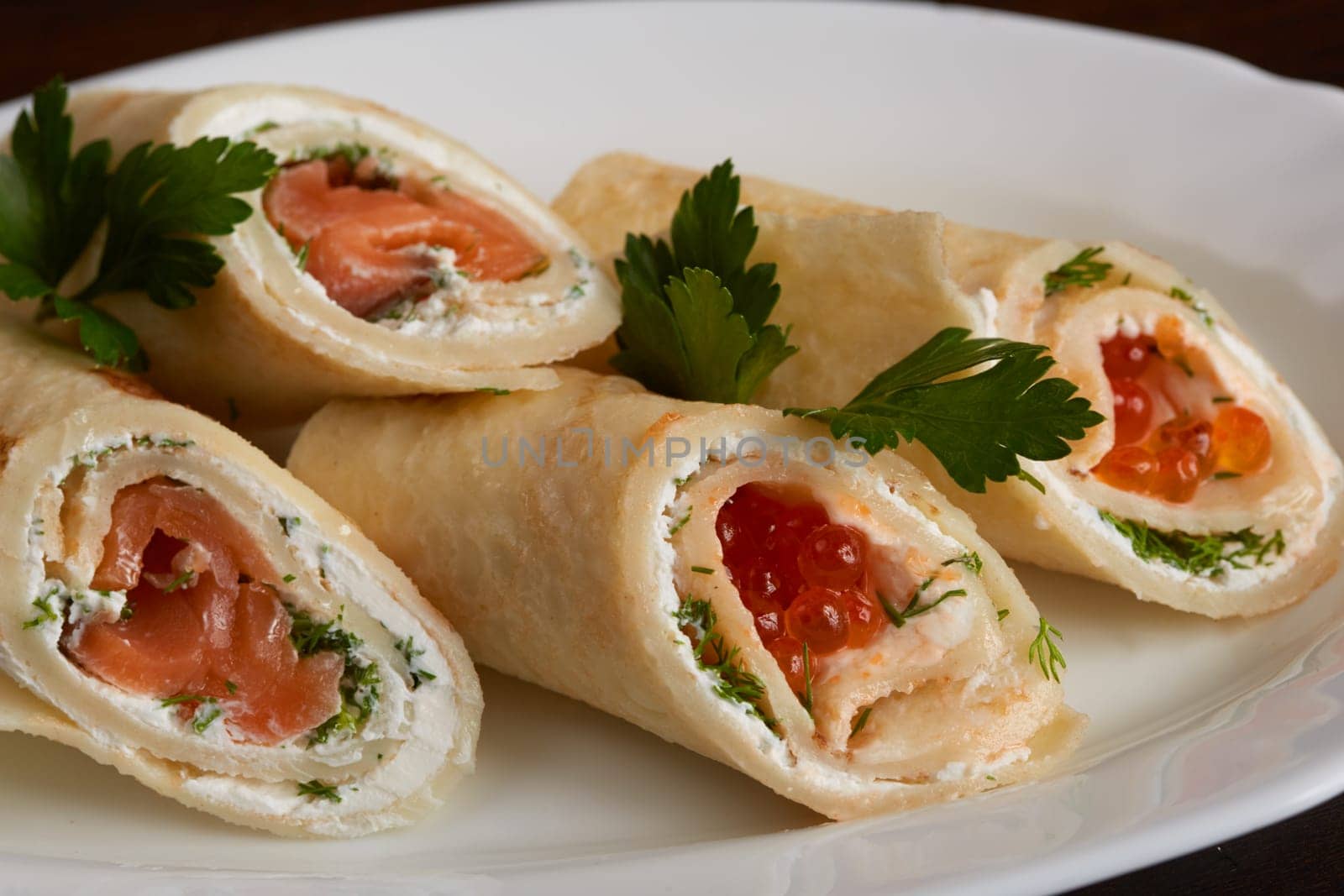 Delicious rolls of pita with salmon and red caviar, close-up