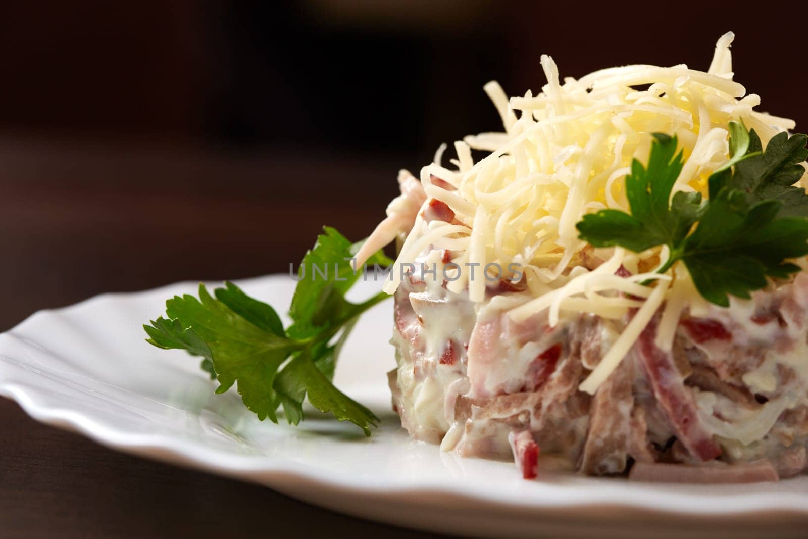 Studio snapshot of meat salad with grated cheese, close-up