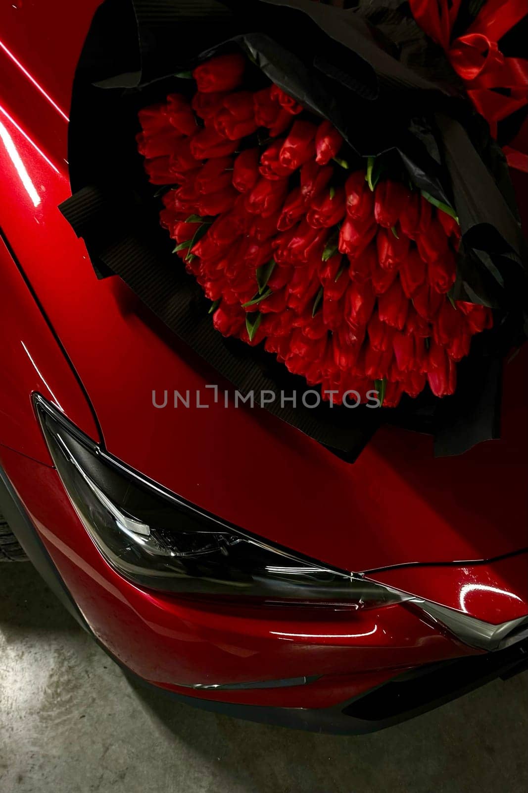 A large bouquet of bright red tulips on a red car by MilaLazo